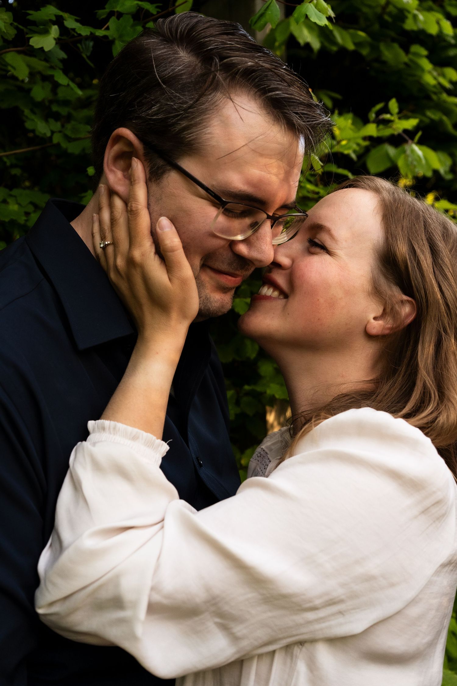 A romantic sequence of close-up shots showing a tender embrace and kiss against a green leafy background.