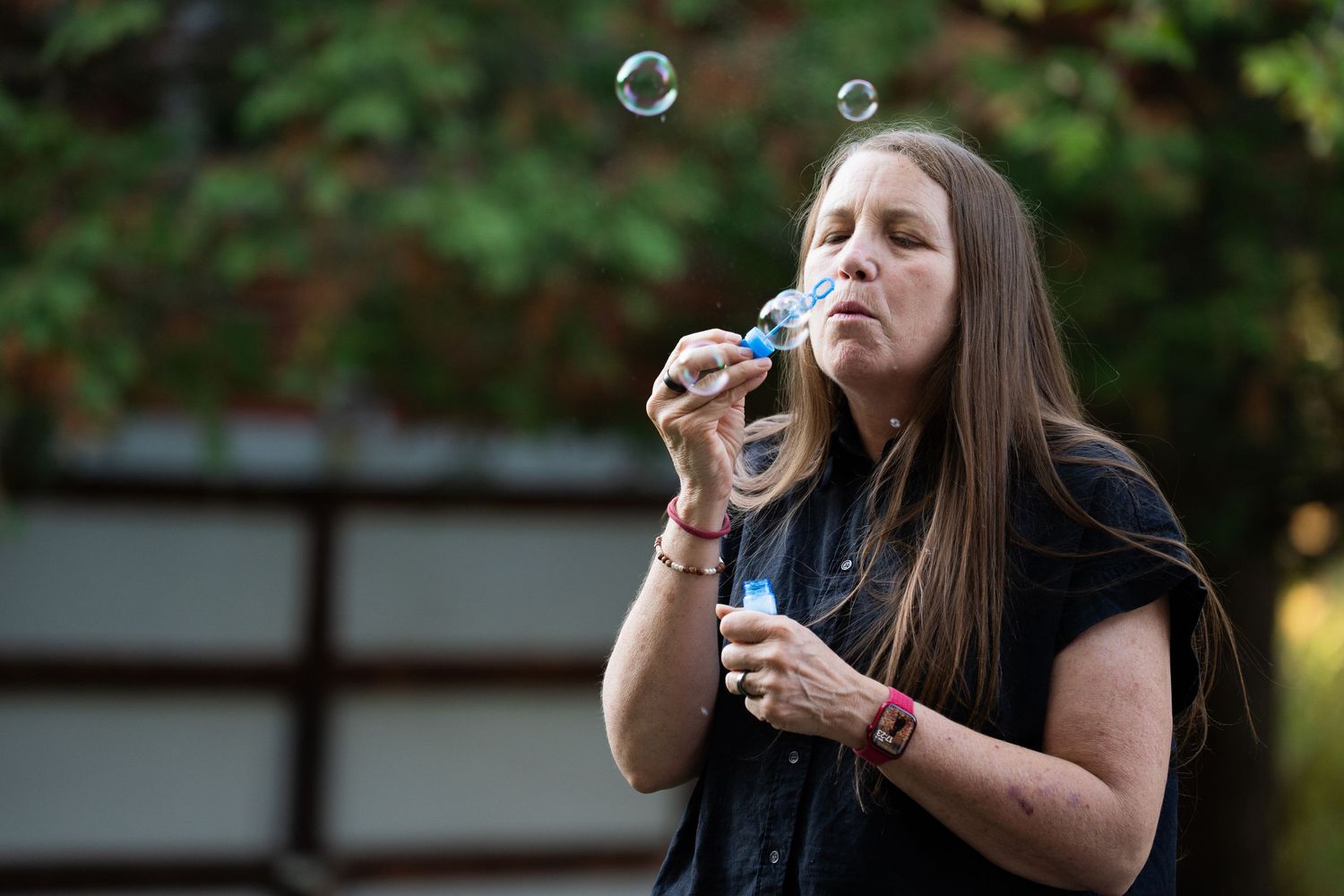 A person blowing bubbles outside in a series of sequential photos showing the bubble-blowing action.