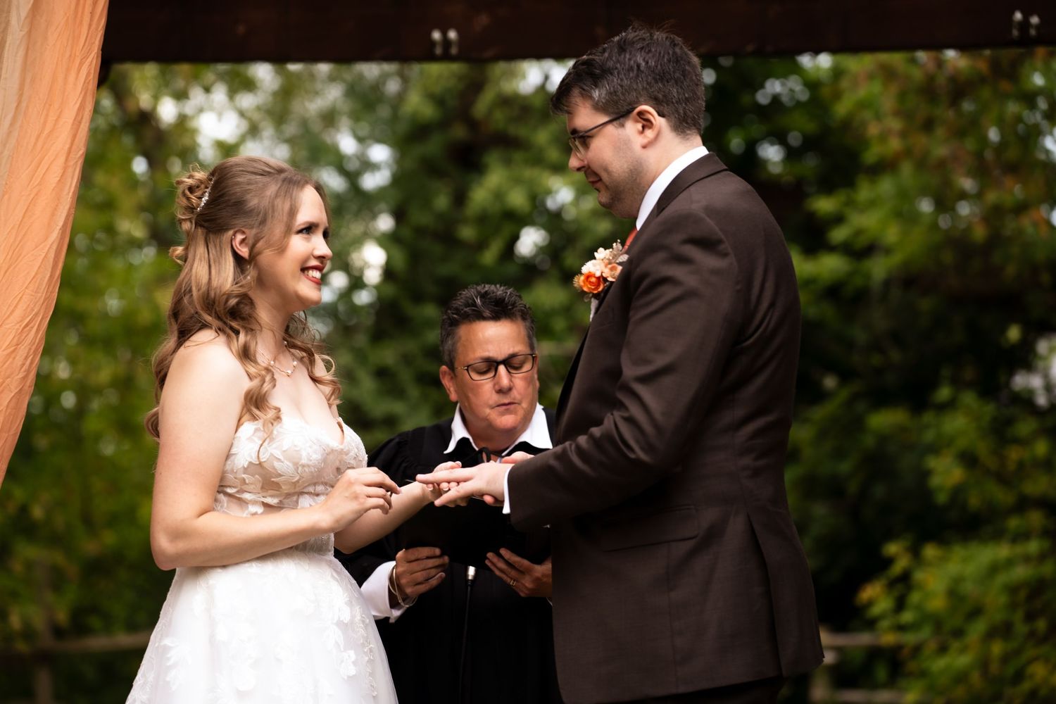 bride is placing ring on the grooms hand
