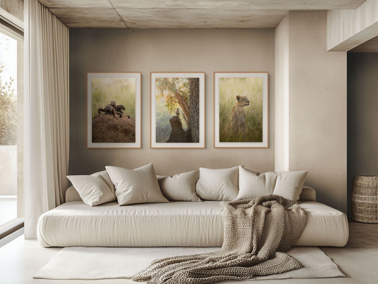 A serene neutral bedroom with a cream sofa, knit throw, and three framed nature art prints on a taupe wall.