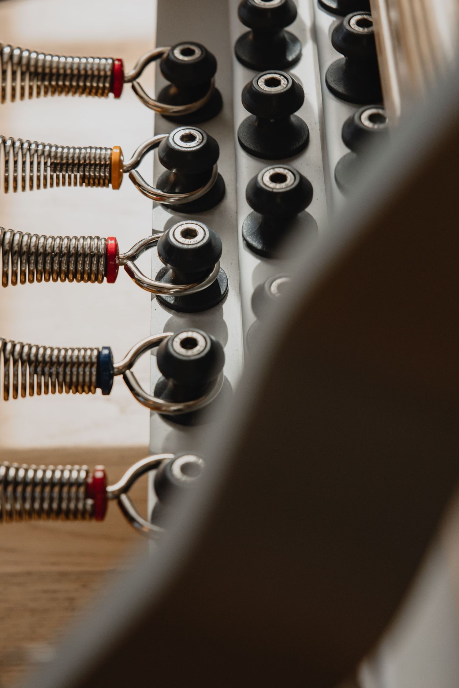 Close-up of industrial springs and black rubber knobs on a metal panel with colored wire connectors.
