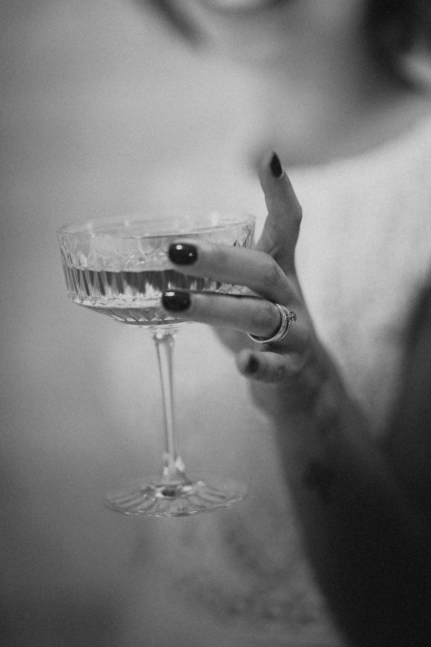 Black and white photo of a woman holding an elegant crystal coupe cocktail glass.