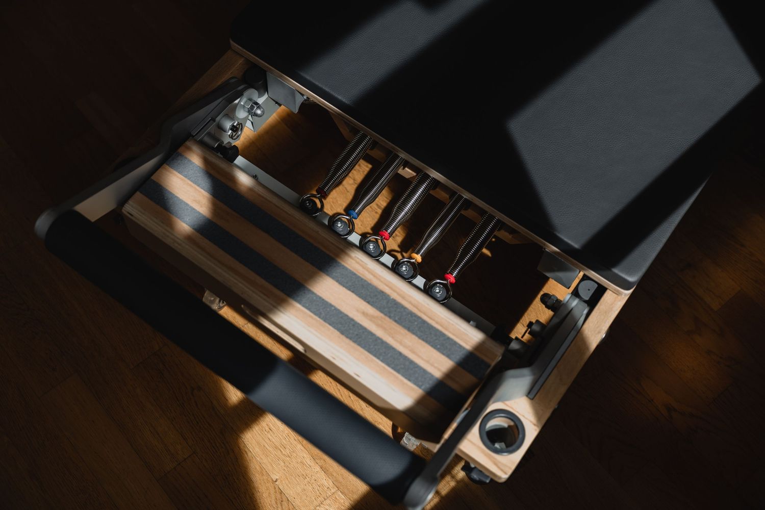 Overhead view of an open drawer with a wooden organizer tray holding tools and supplies on a dark floor.