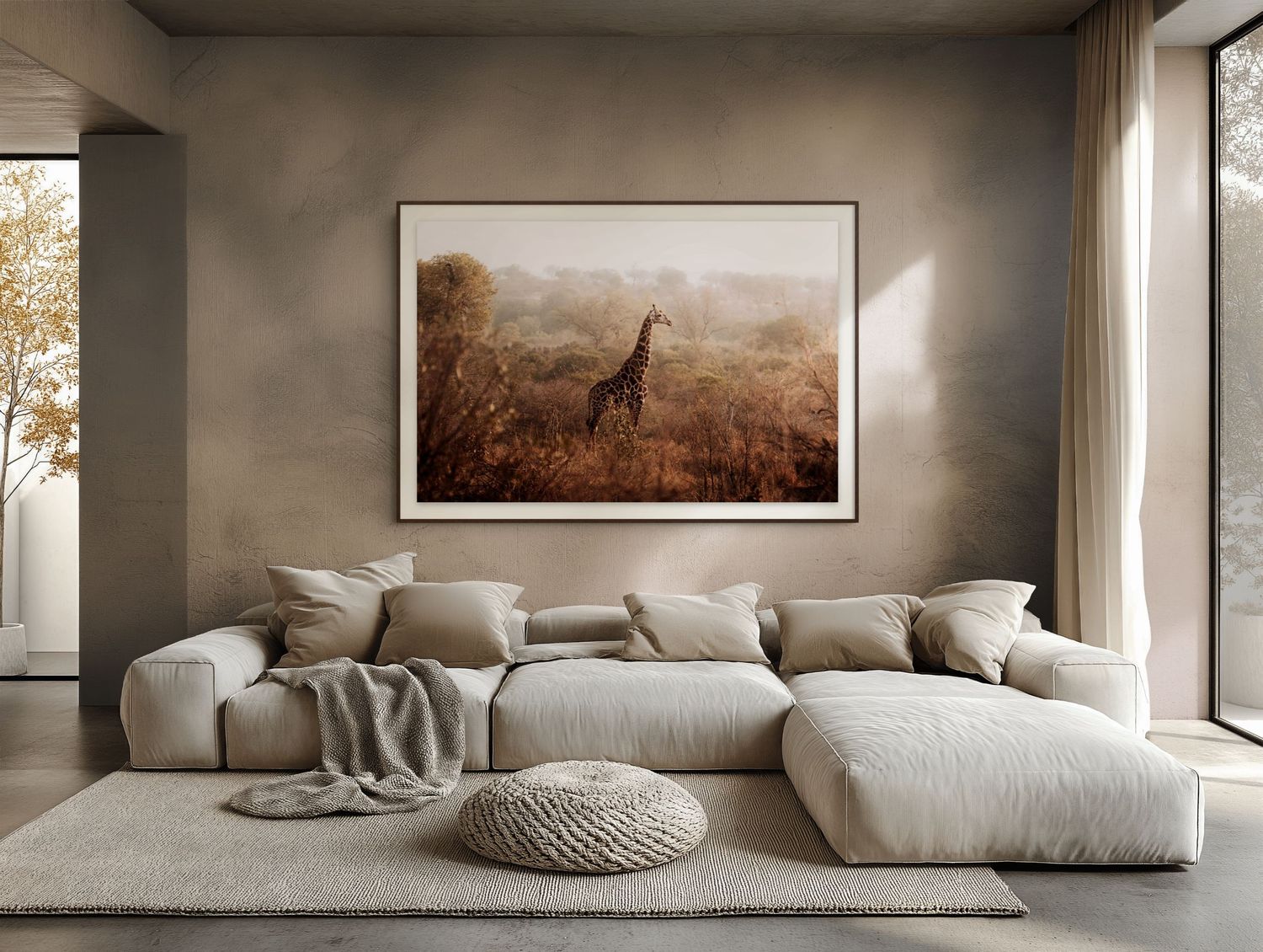 A framed giraffe wildlife photograph hangs above a beige sectional sofa in a warm, neutral-toned modern living room.