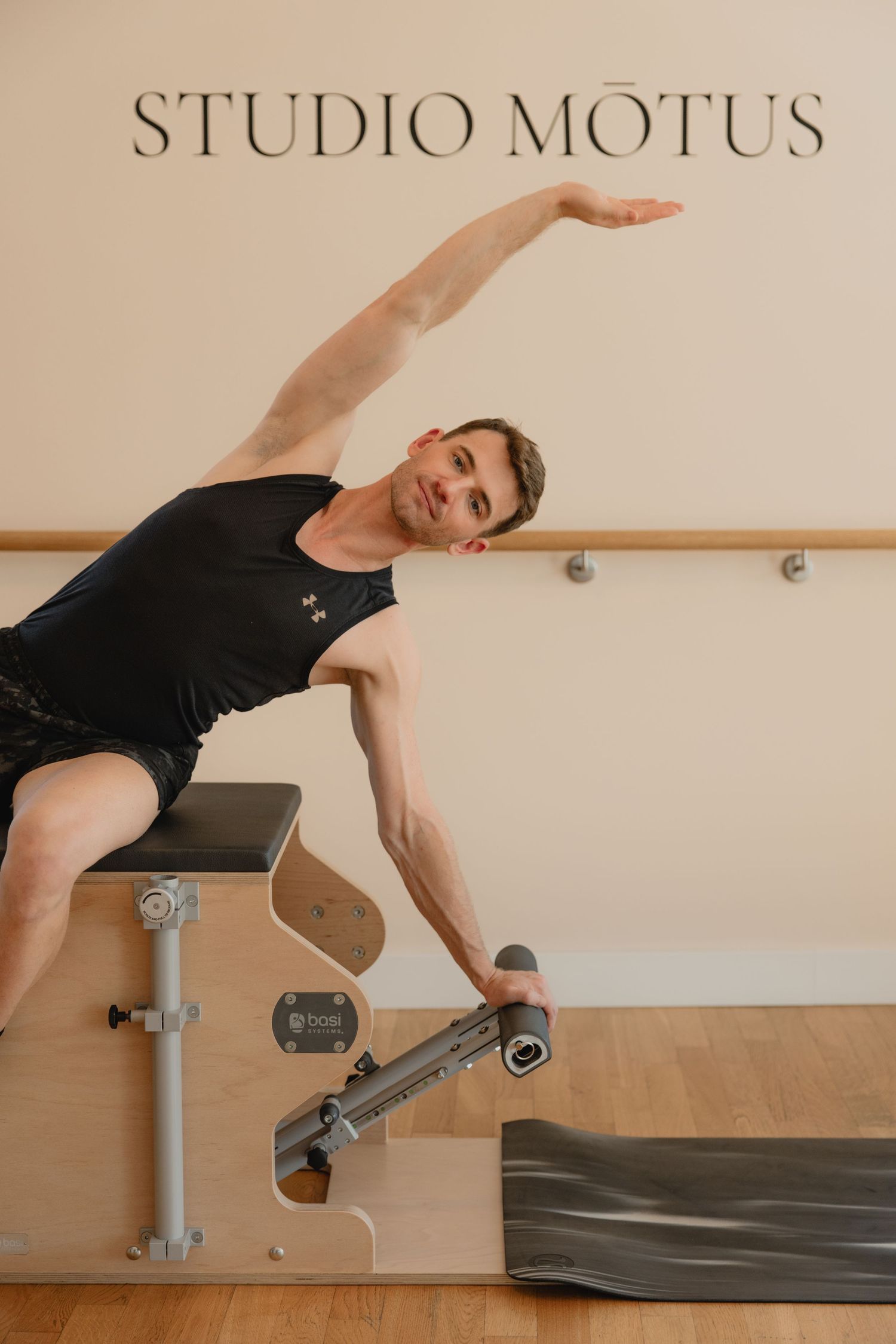 Man performing a side bend stretch on a Pilates Wunda Chair at Studio Motus.