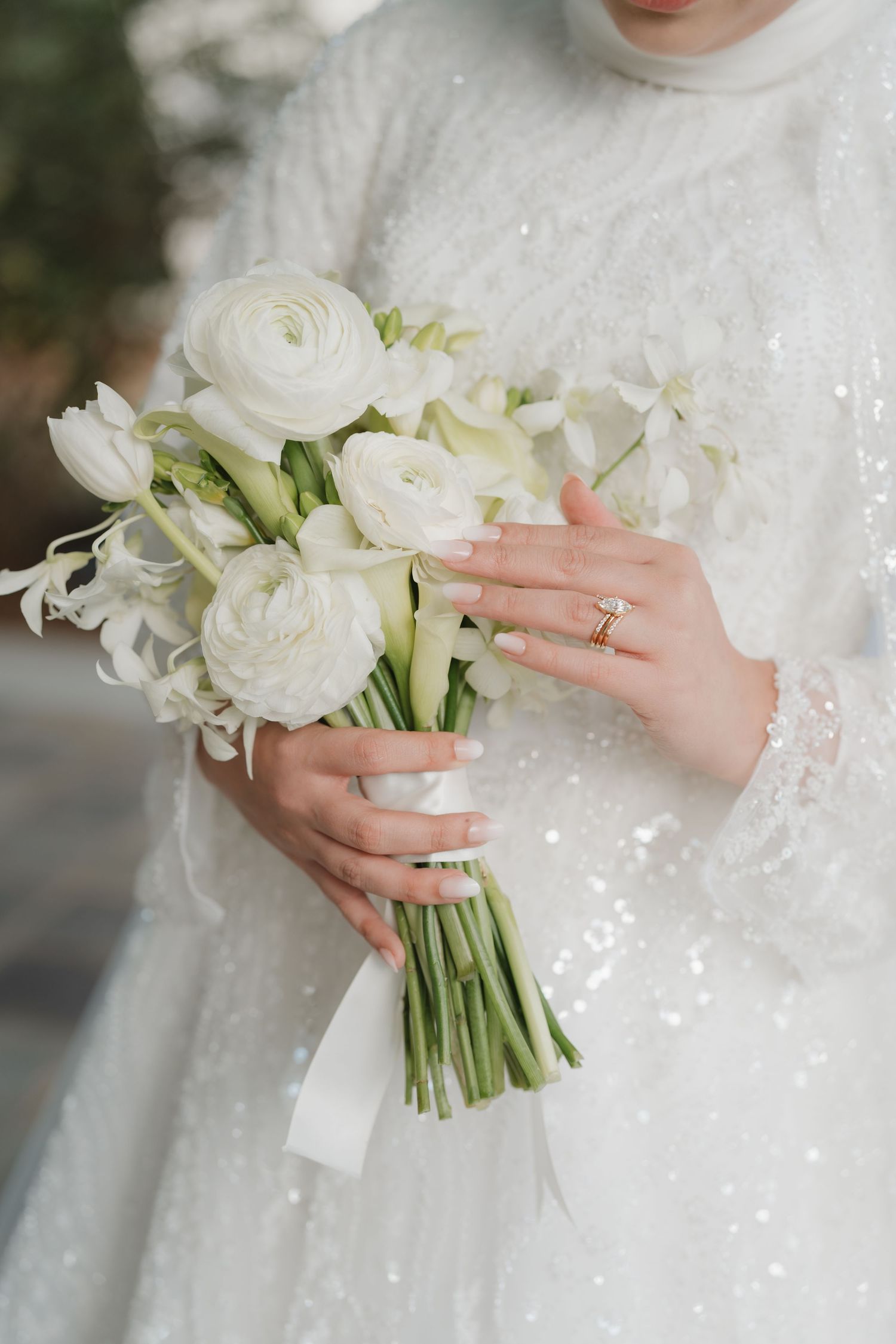 A close-up series of hands holding an elegant white bridal bouquet with roses and lilies against a white lace dress.