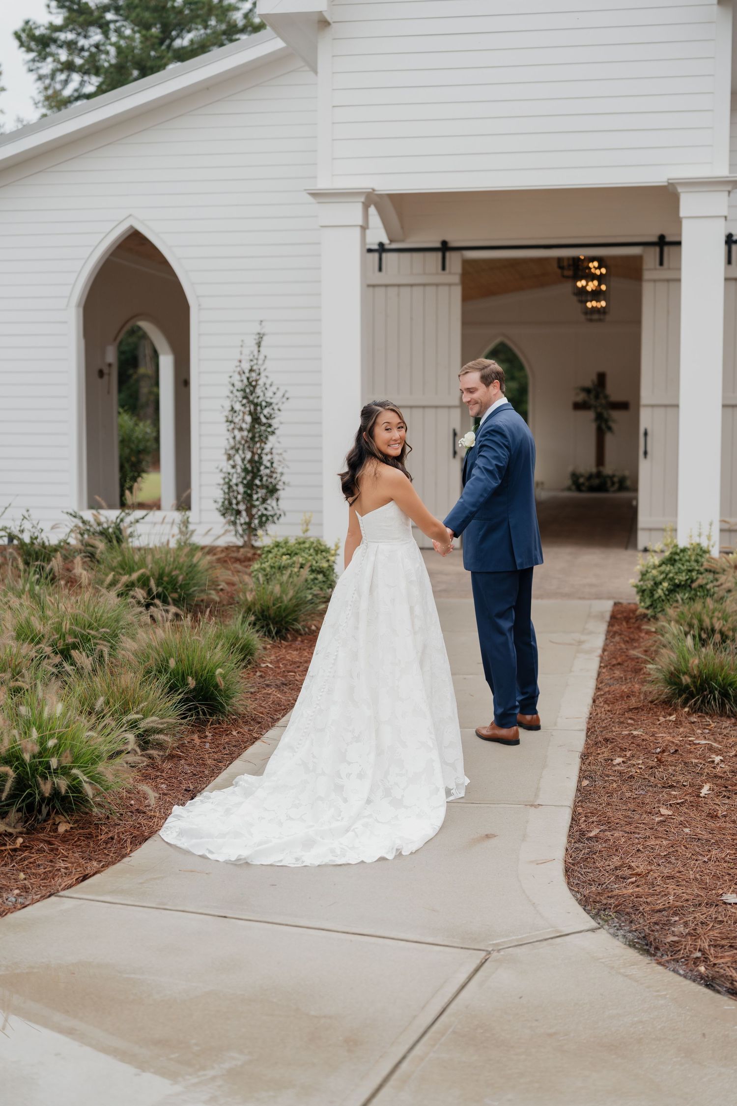 A series of wedding first look photos showing a couple in white dress and navy suit meeting at an elegant white chapel entrance.