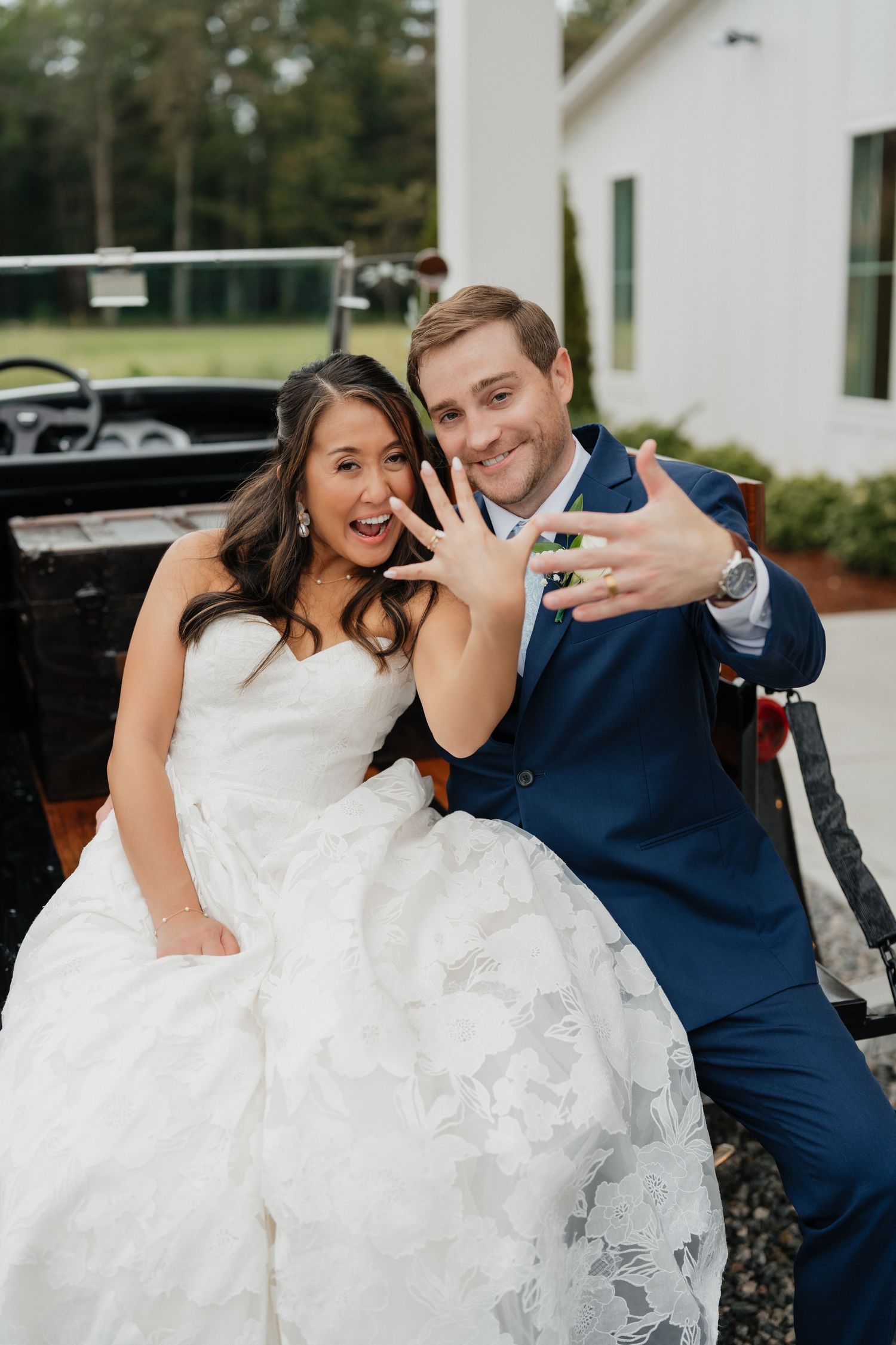 Newlywed couple shares joyful laughter during outdoor wedding photo session in navy and white attire.