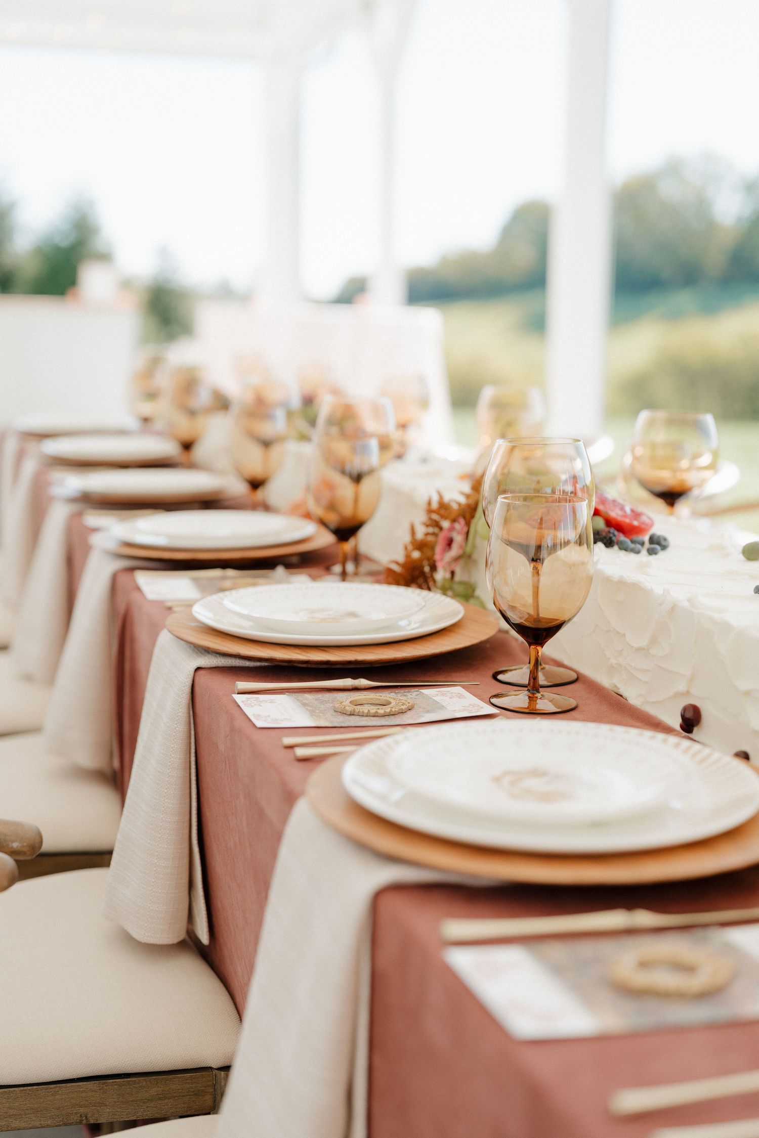 Elegant table settings with white plates, gold chargers, and blush pink linens create a sophisticated dining atmosphere.