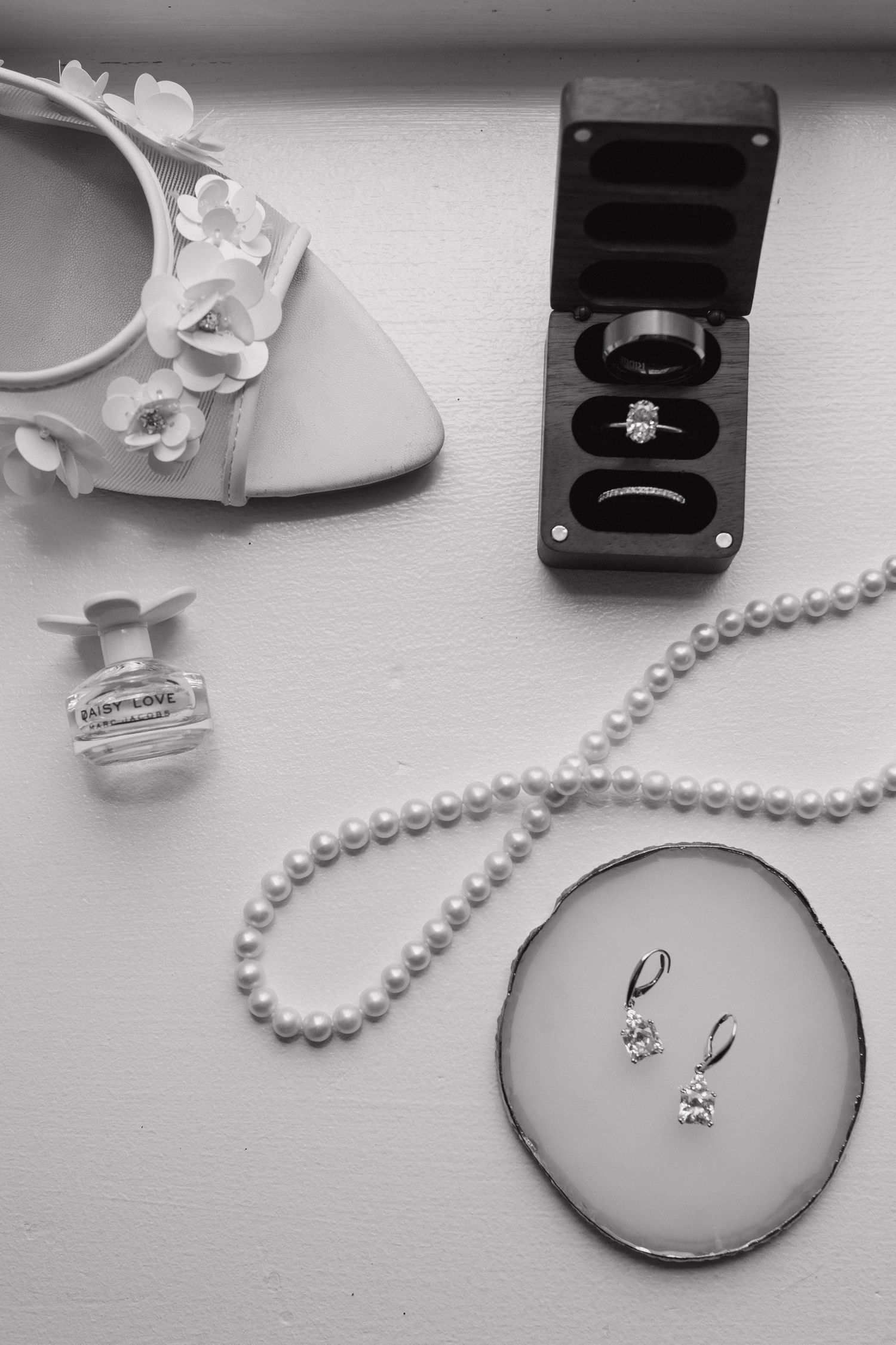 Sequence of black and white photos showing pearl necklace and engagement ring boxes in artistic arrangement.