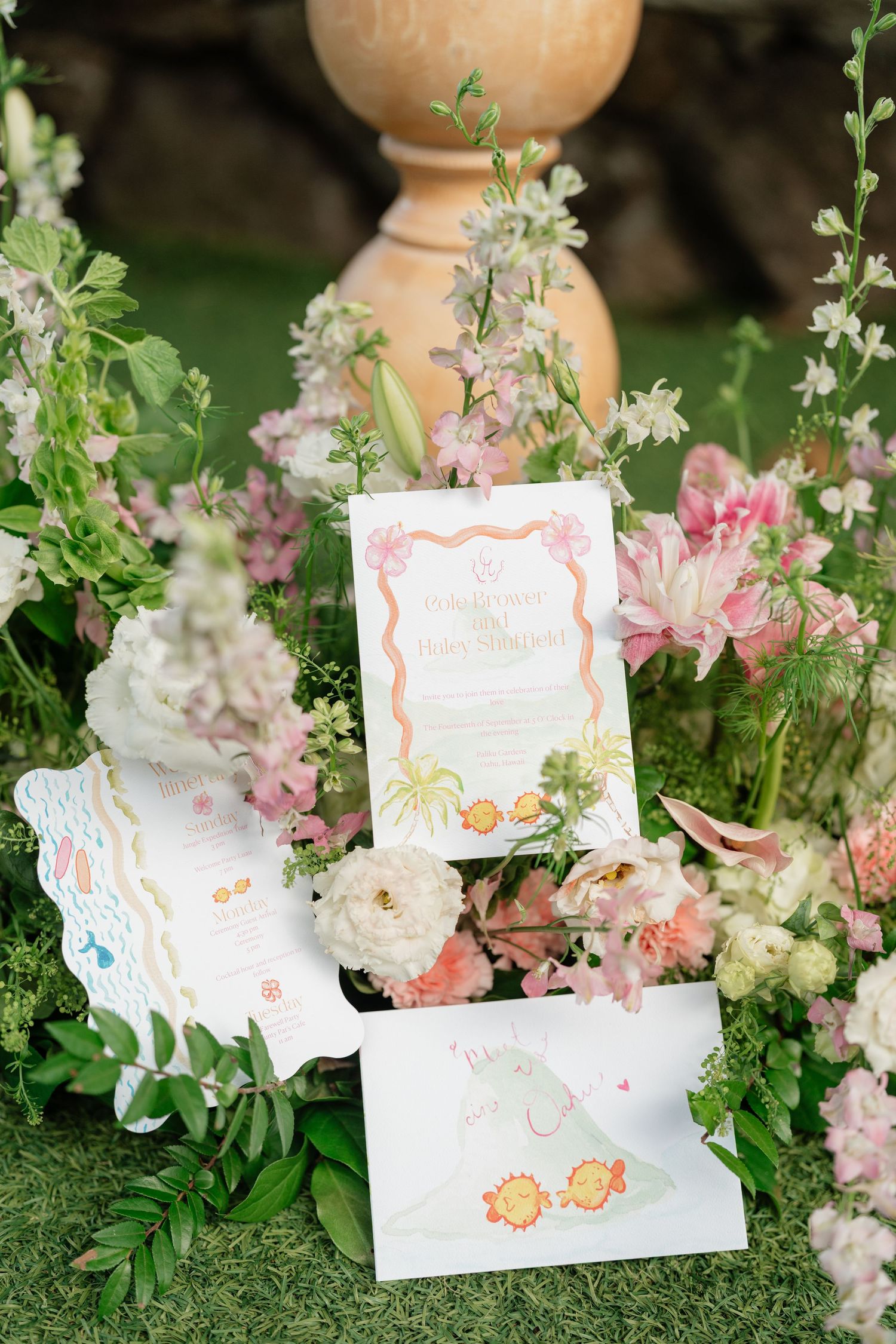 Elegant wedding stationery suite displayed among pink and white florals, featuring illustrated cards with botanical designs.
