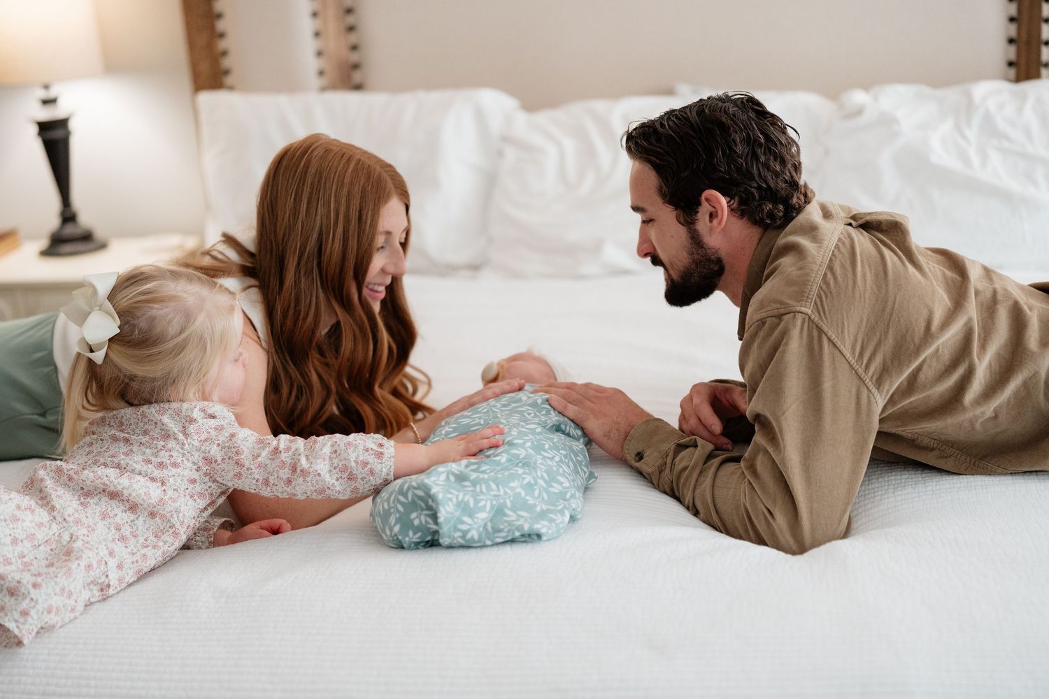 Romantic couple lying on white bedding shares intimate moments in a series of connected lifestyle photographs.