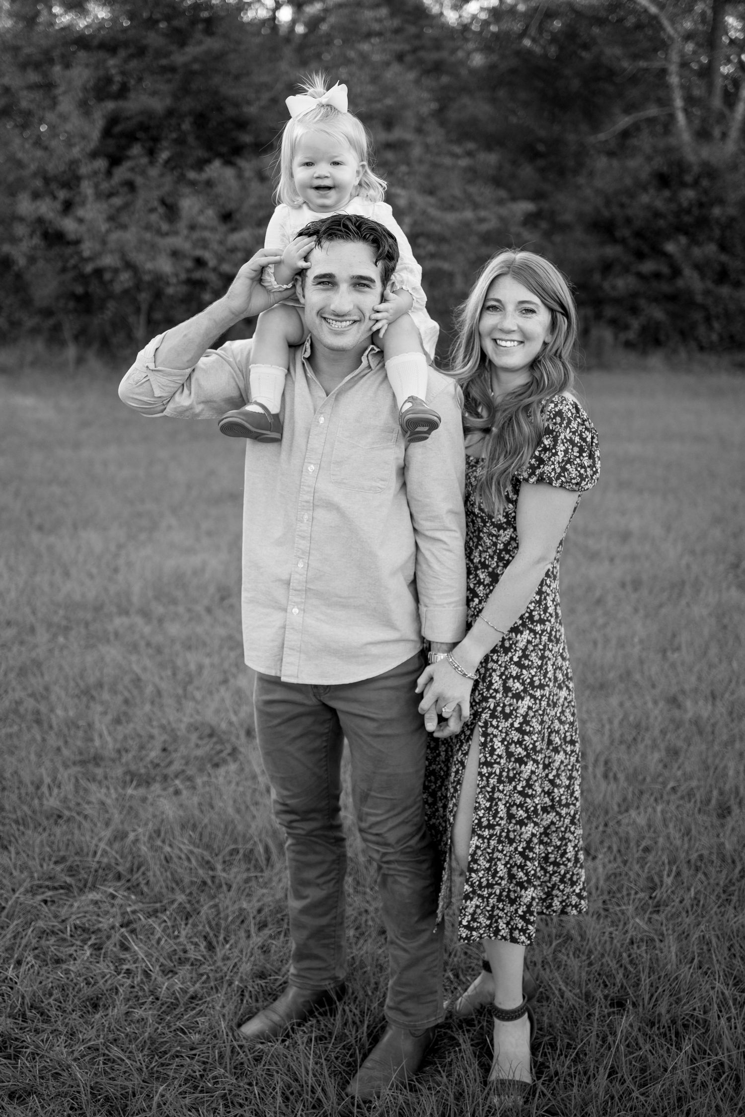 Beautiful black and white portrait of family enjoying outdoor photo session in a grassy field.