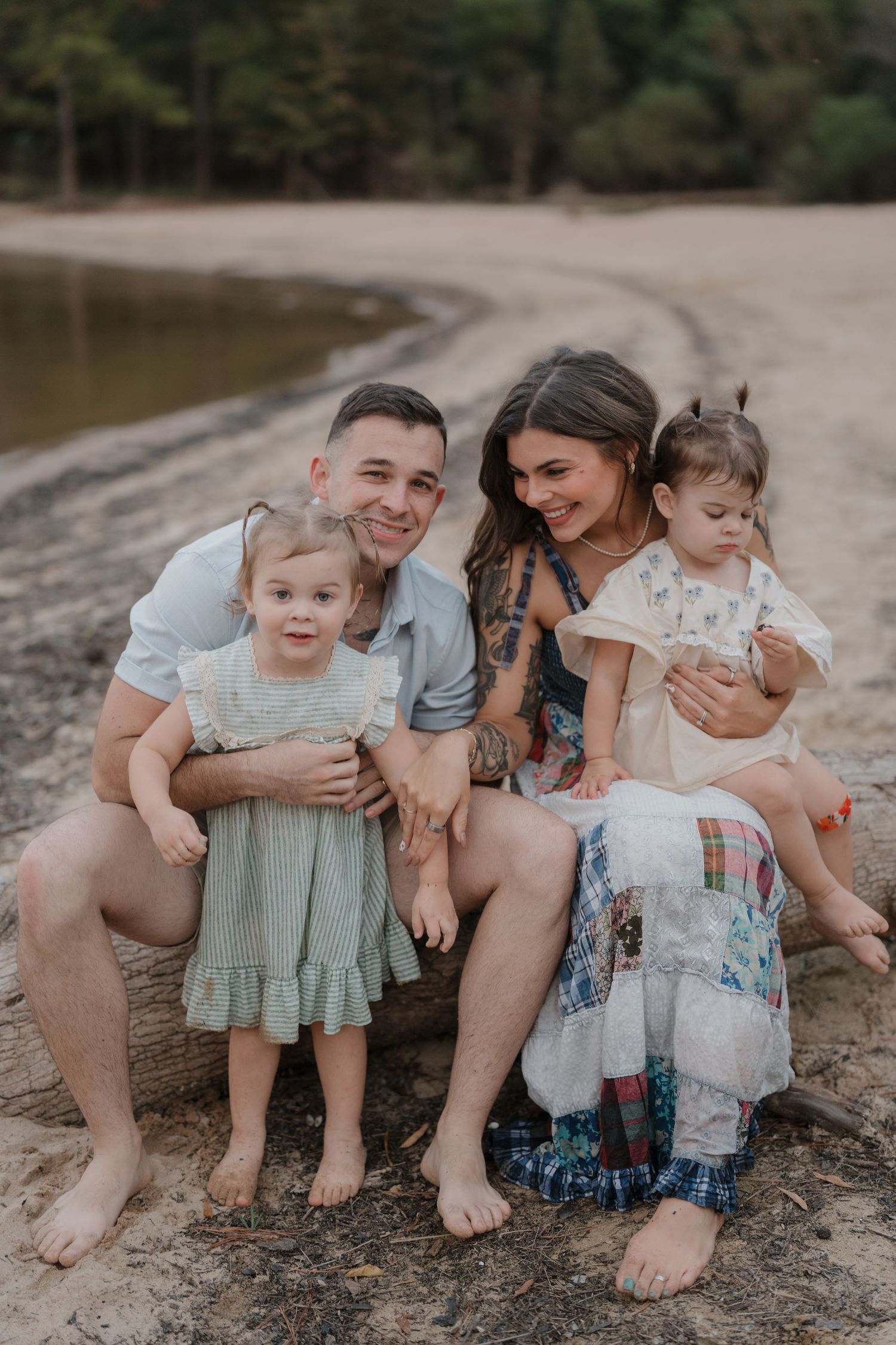 Family sitting together on a beach shore in casual summer attire sharing intimate moments.