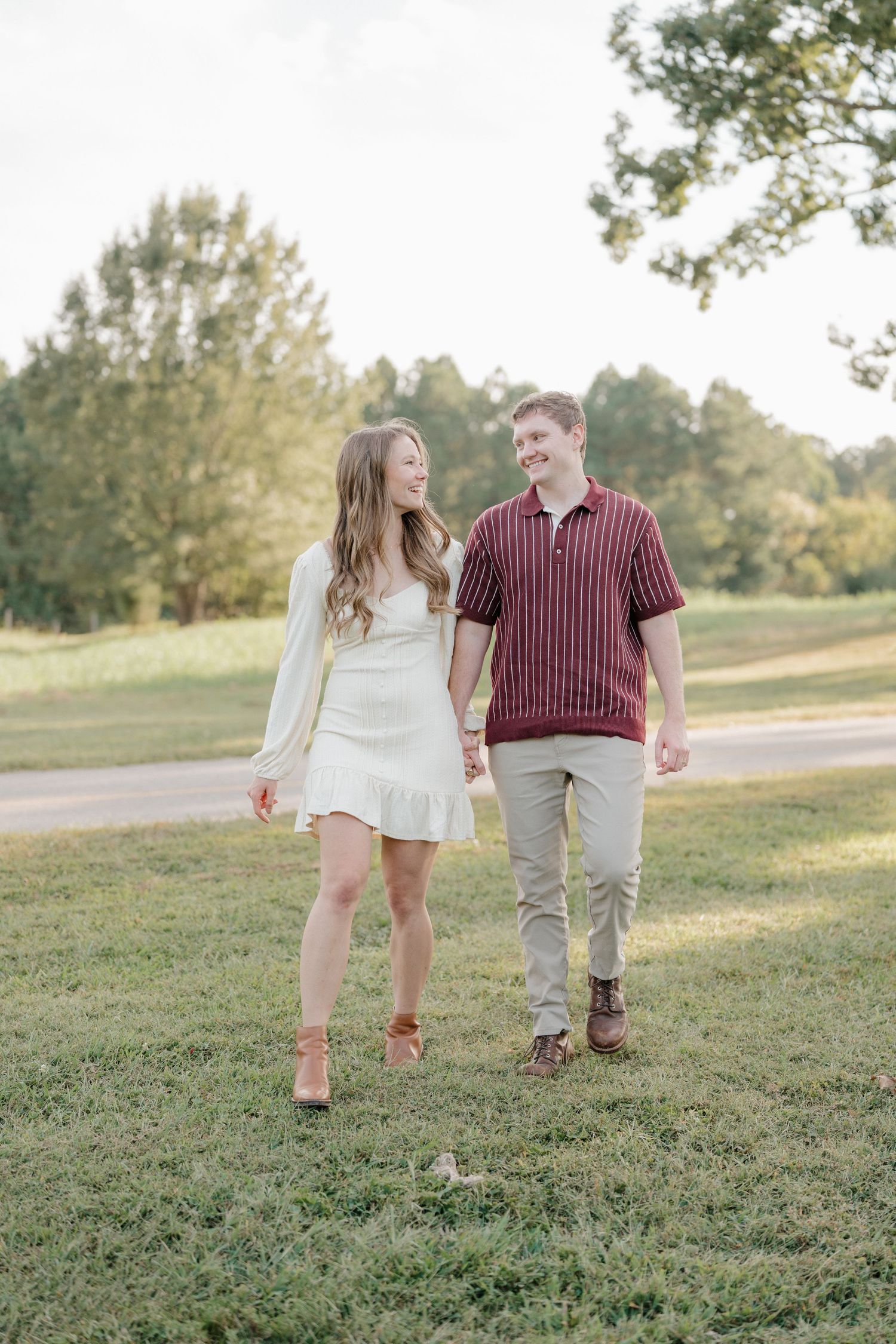 A couple walks hand in hand through a grassy field on a sunny afternoon, captured in a series of candid moments.