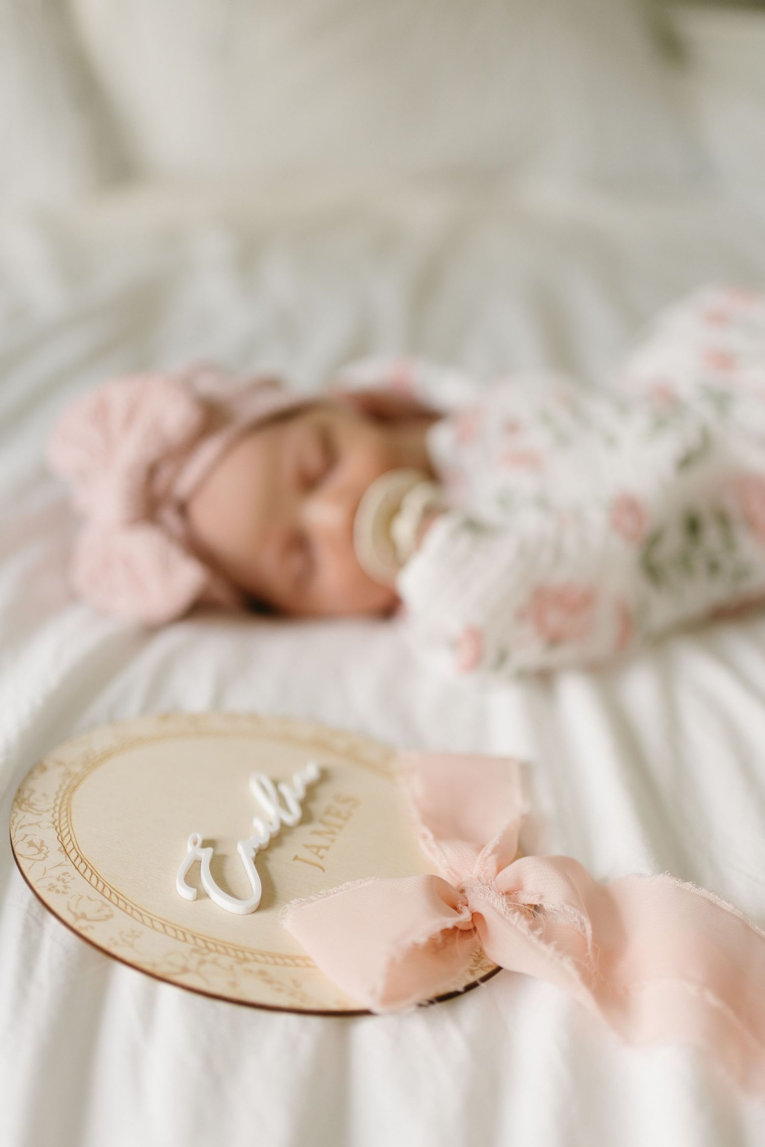 Delicate wedding favors with monogrammed tags tied with soft pink ribbons lay on white linens.