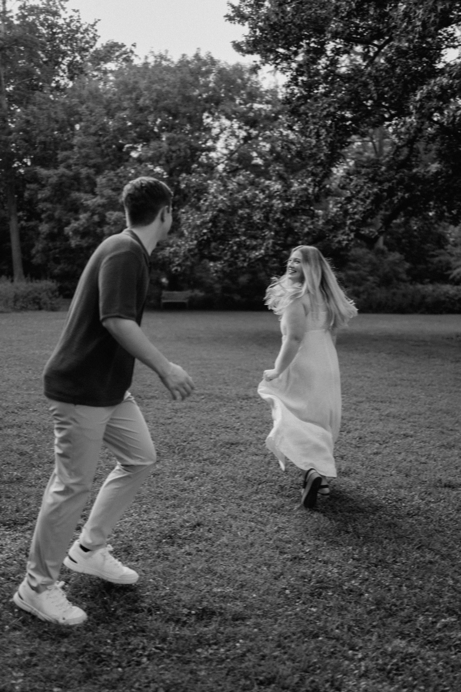 Two people playing together on a grassy lawn while enjoying an energetic game in a park setting.
