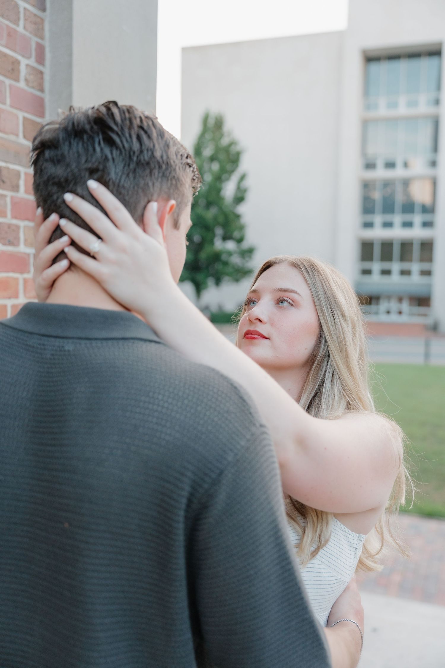 A romantic couple embraces outside a brick building during an intimate photo series.