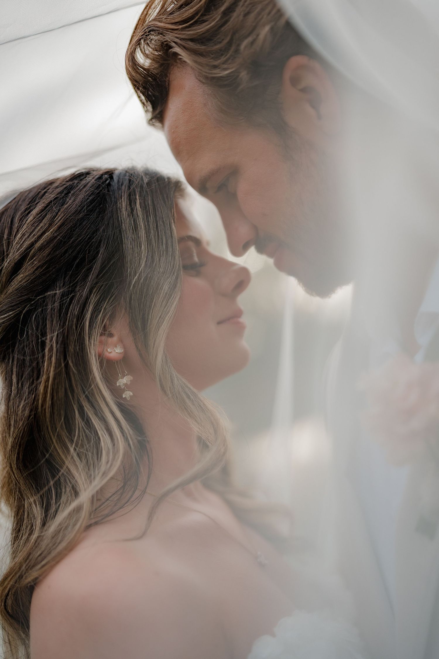 Romantic couple sharing an intimate moment in soft dreamy lighting with their faces close together.
