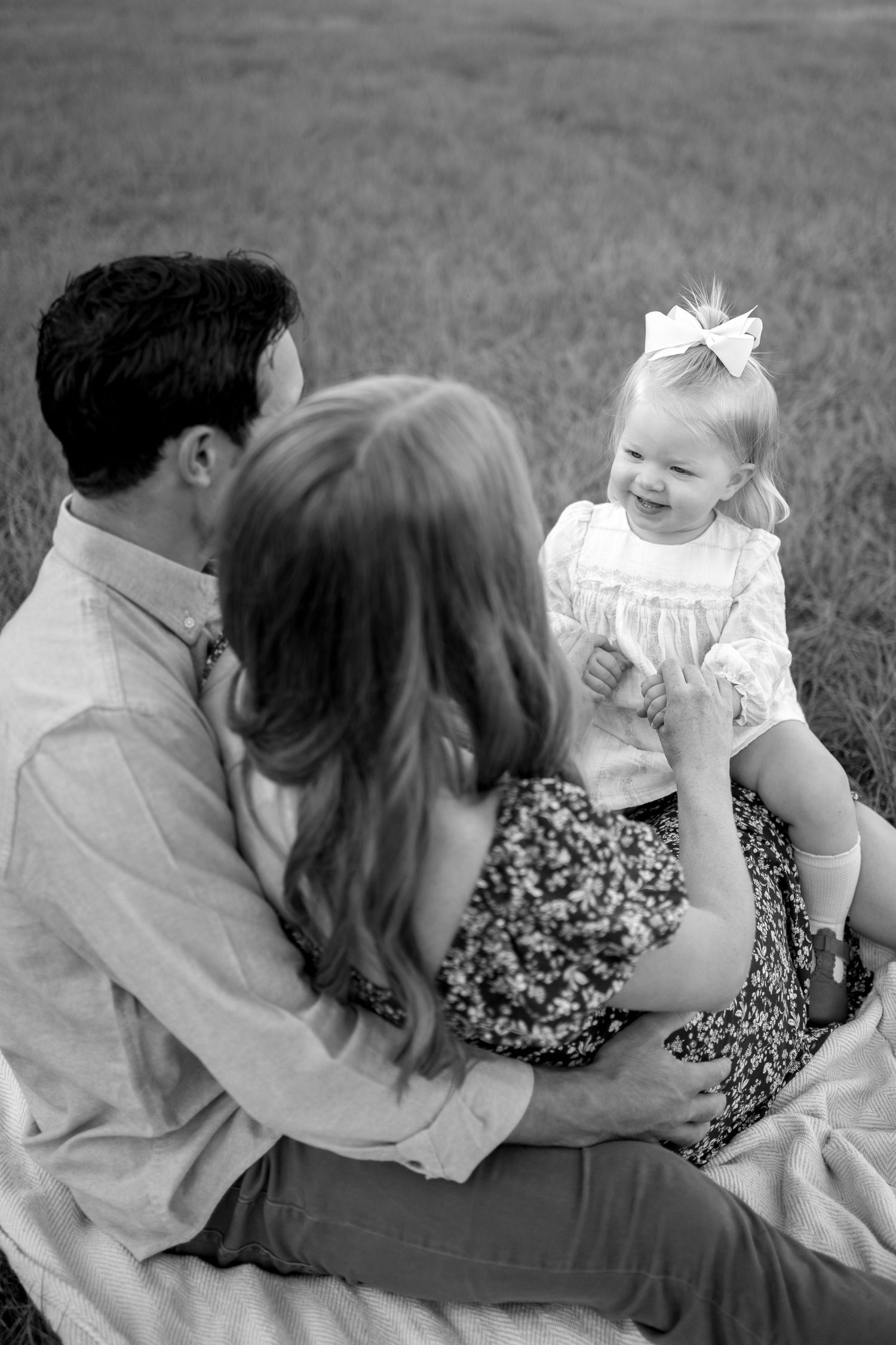 Black and white photo sequence showing a family embracing and sitting together outdoors on grass.