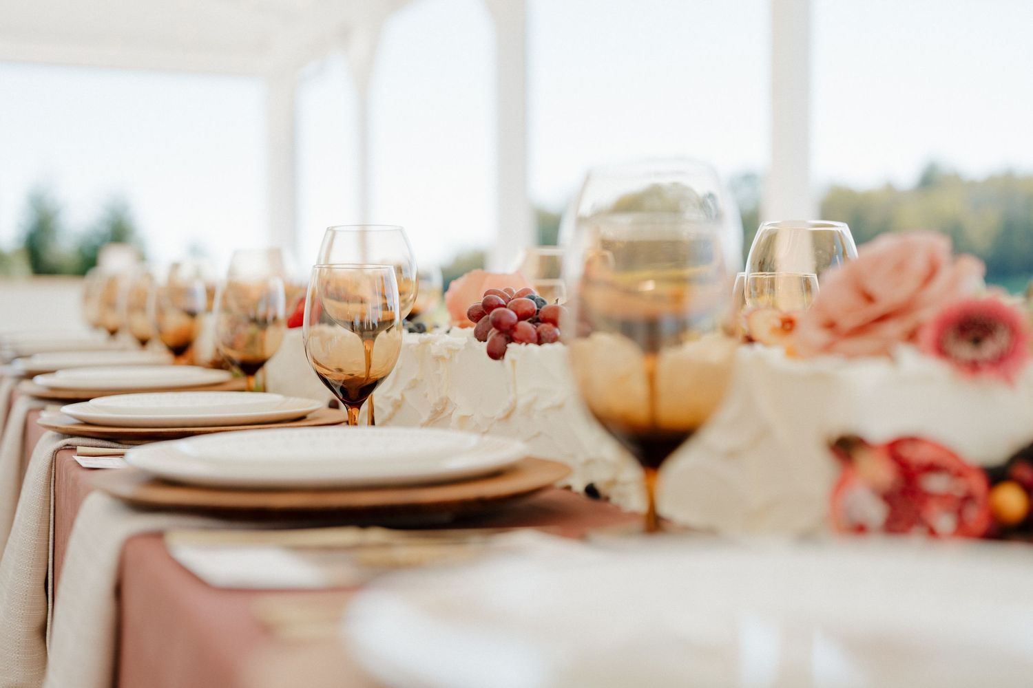 Elegant table settings with pink floral arrangements and gold accents create a romantic wedding reception atmosphere.