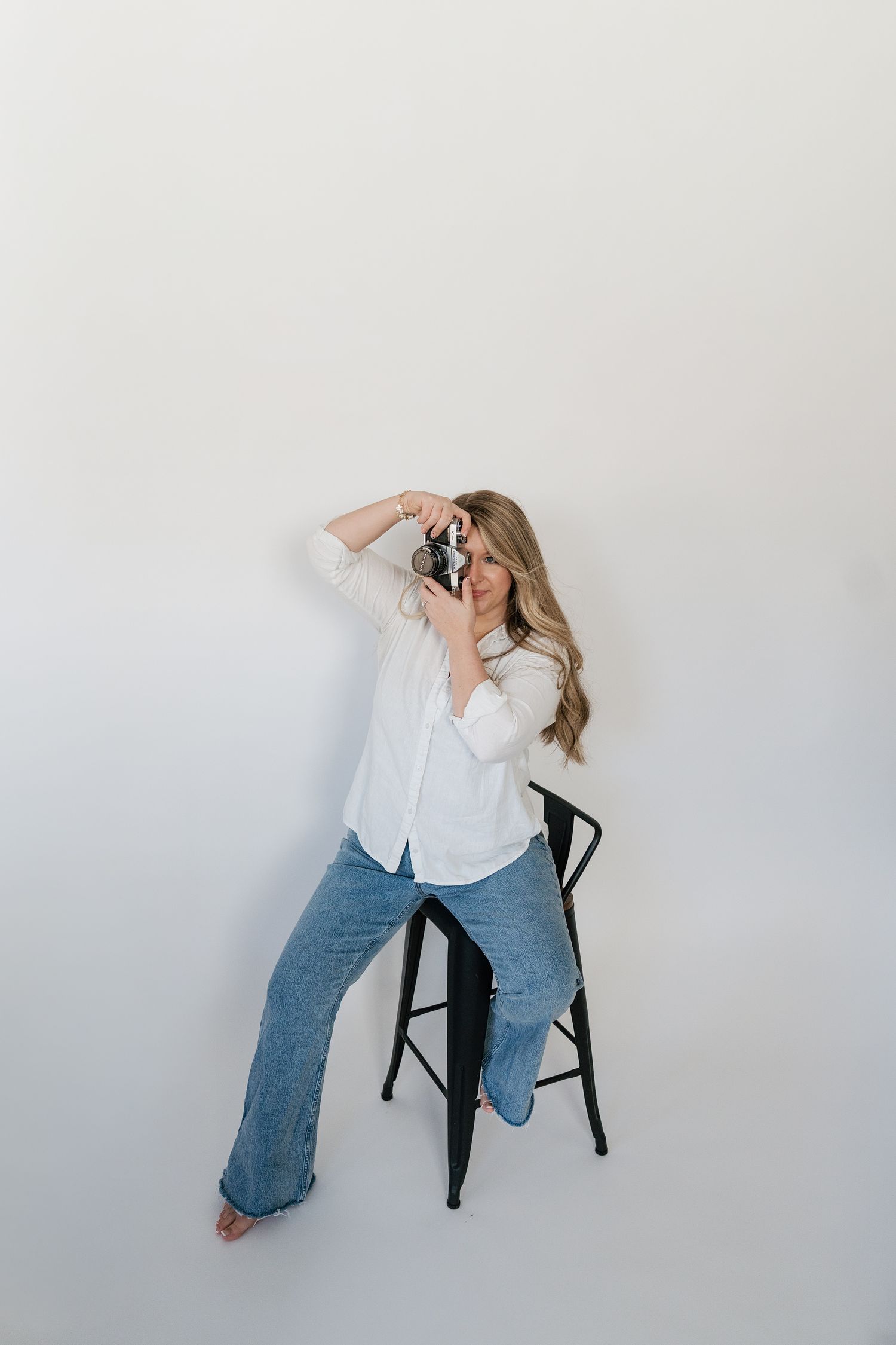 A person in a white shirt and blue jeans poses on a black stool against a white background in four different positions.