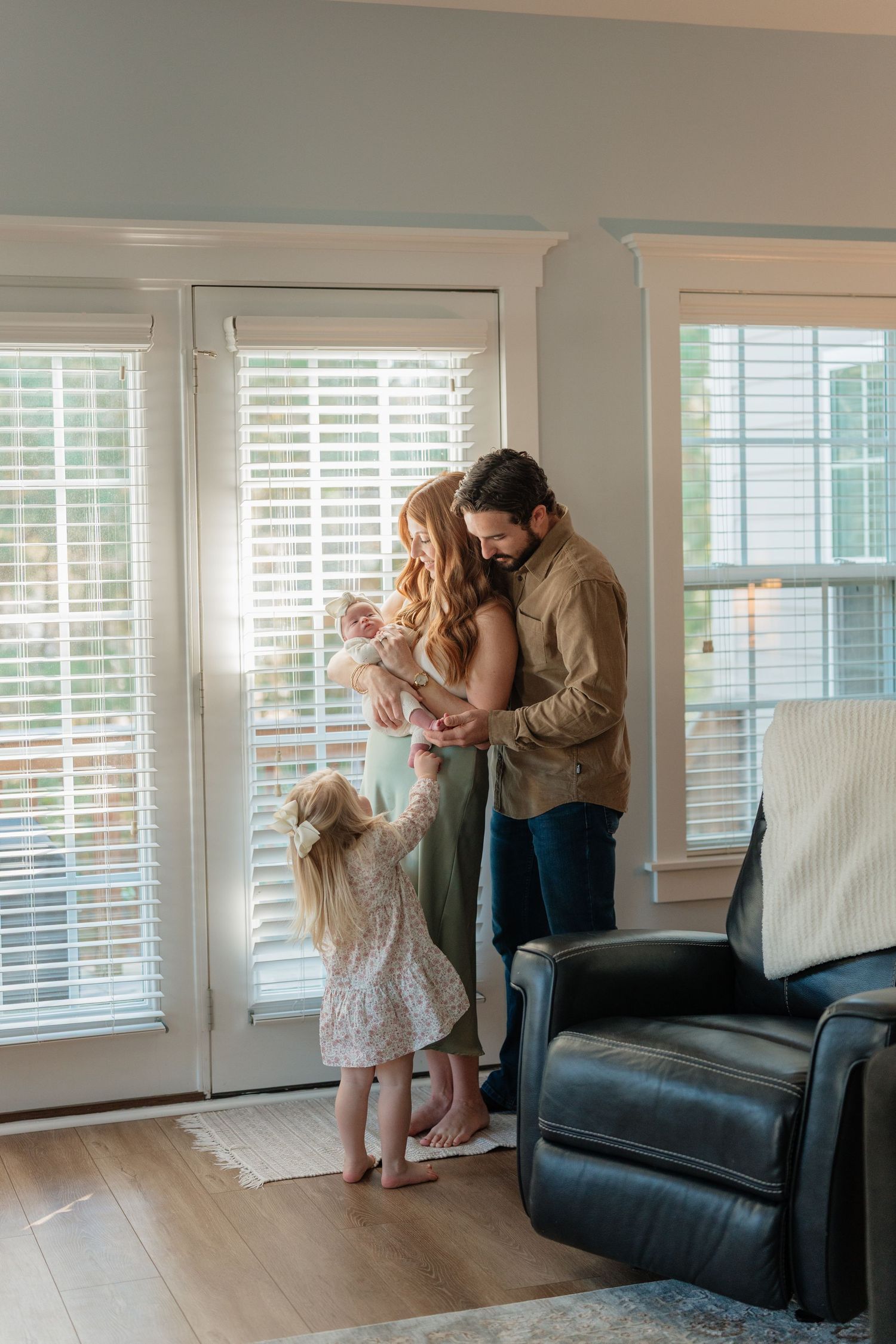 A sequence of tender moments between parent and child in a bright living room with white shutters and hardwood floors.