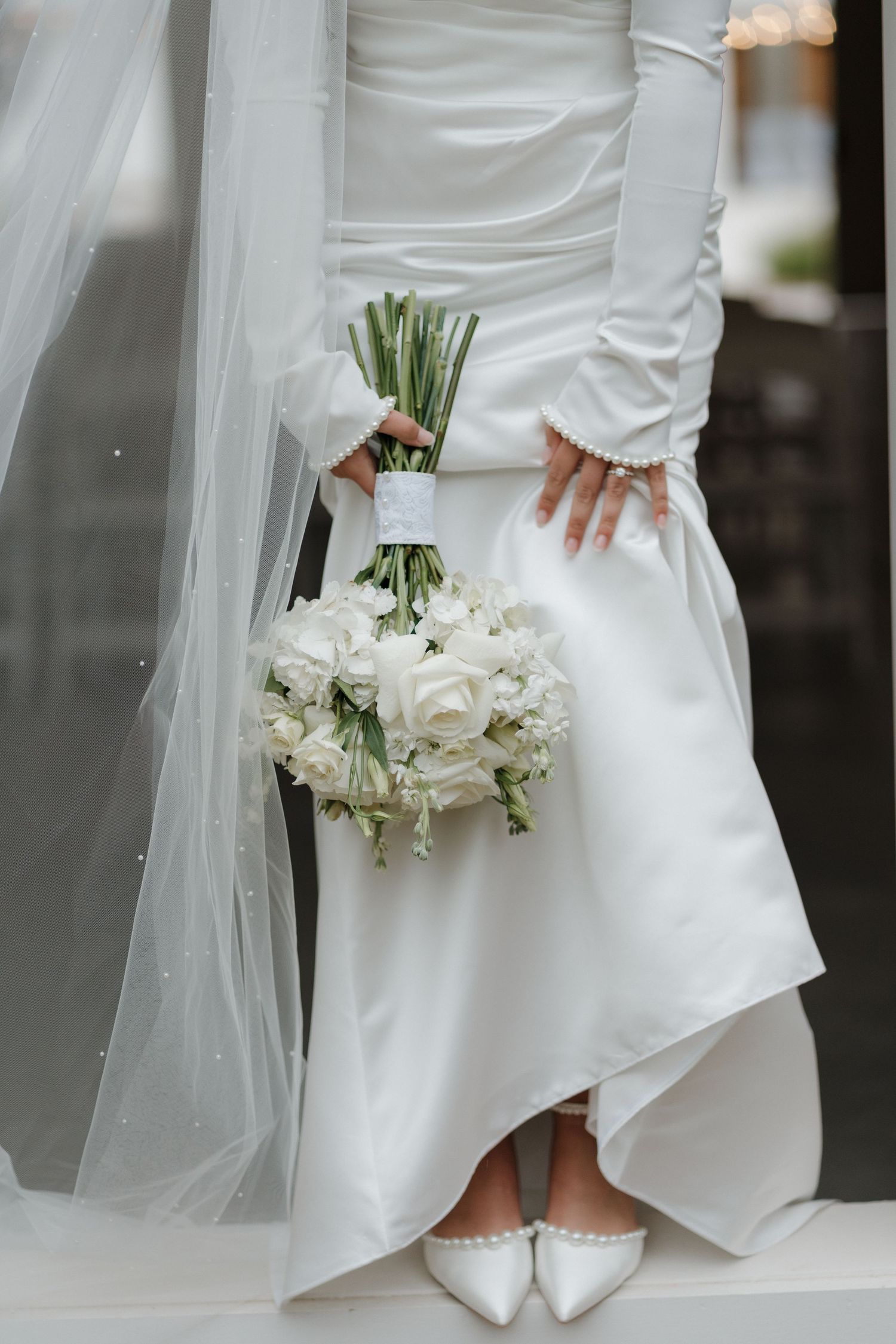 Close-up details of a white wedding dress with flowing veil and delicate white rose bouquet from different angles.