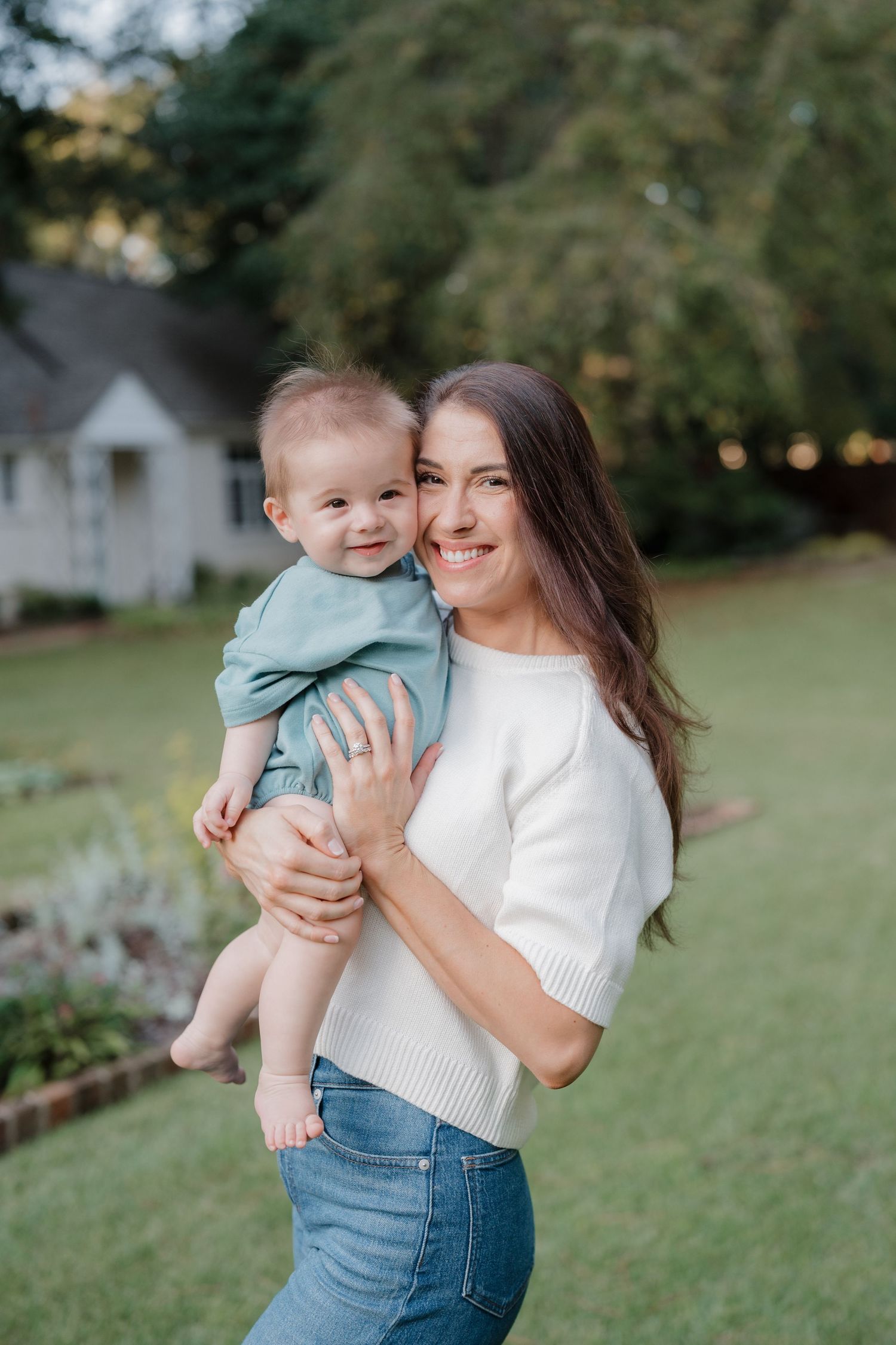 A parent and child share joyful moments together outdoors in a grassy backyard setting.
