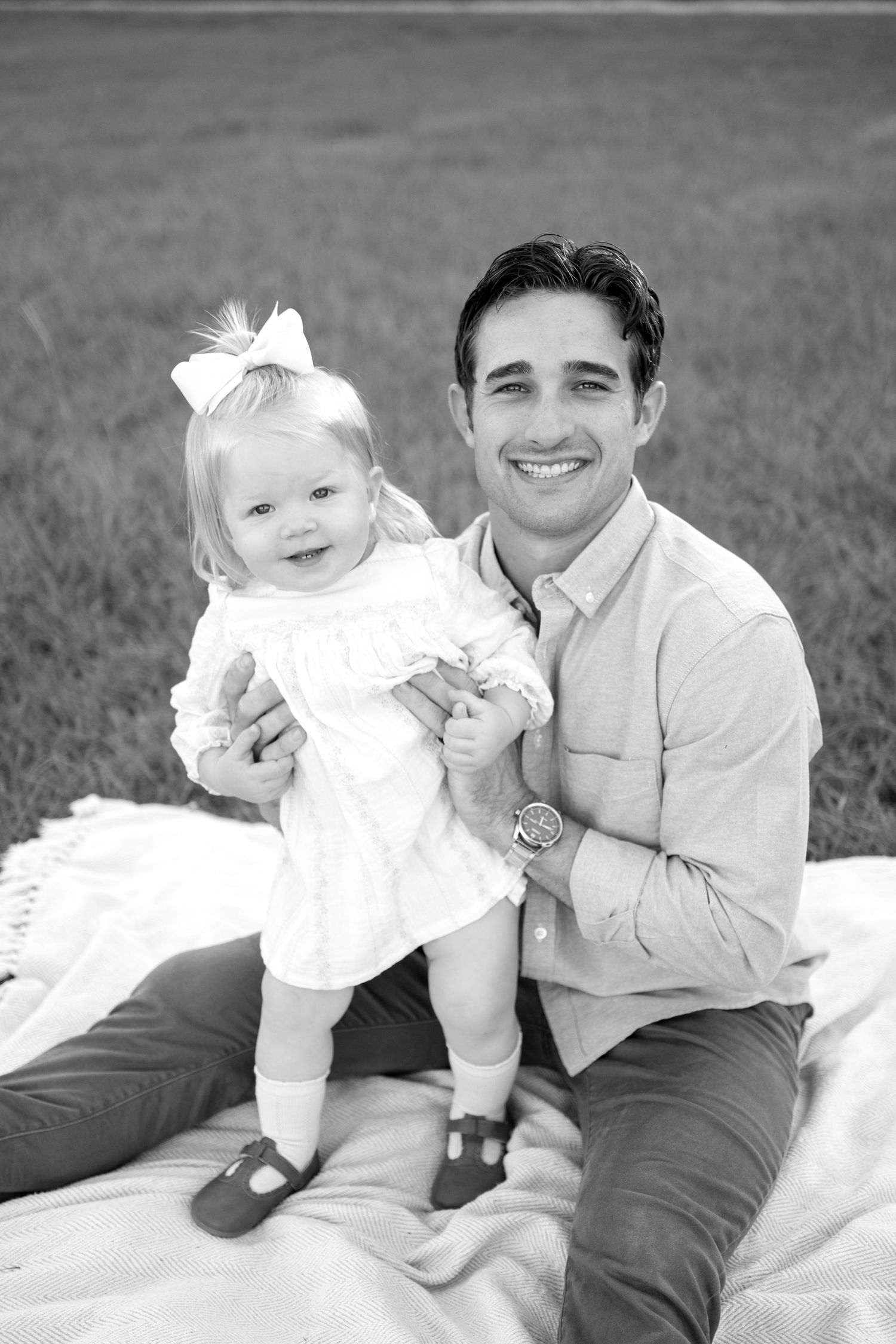 A heartwarming black and white portrait on a blanket in the grass on a sunny day.