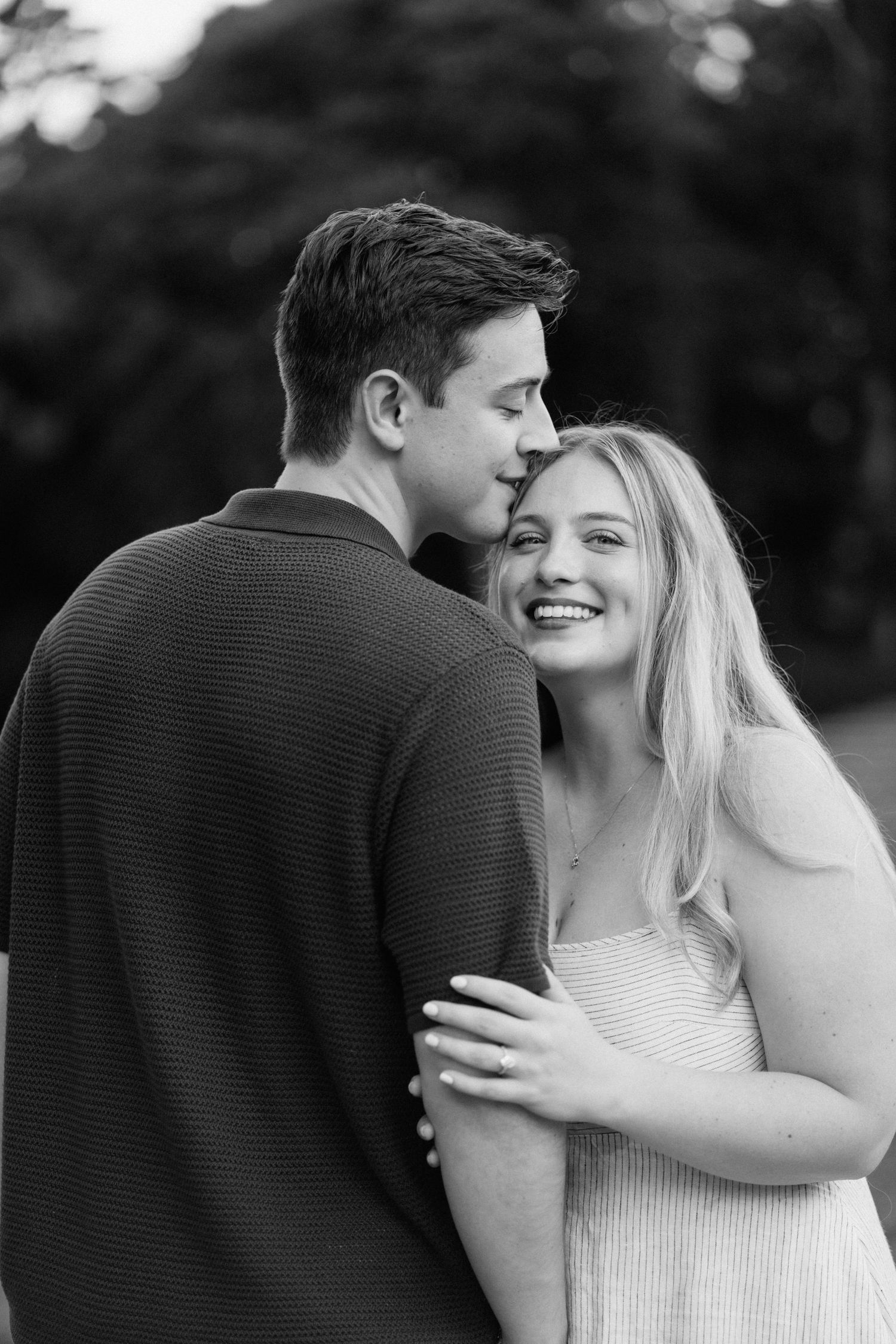 Black and white portrait of a couple sharing an intimate moment while embracing outdoors.