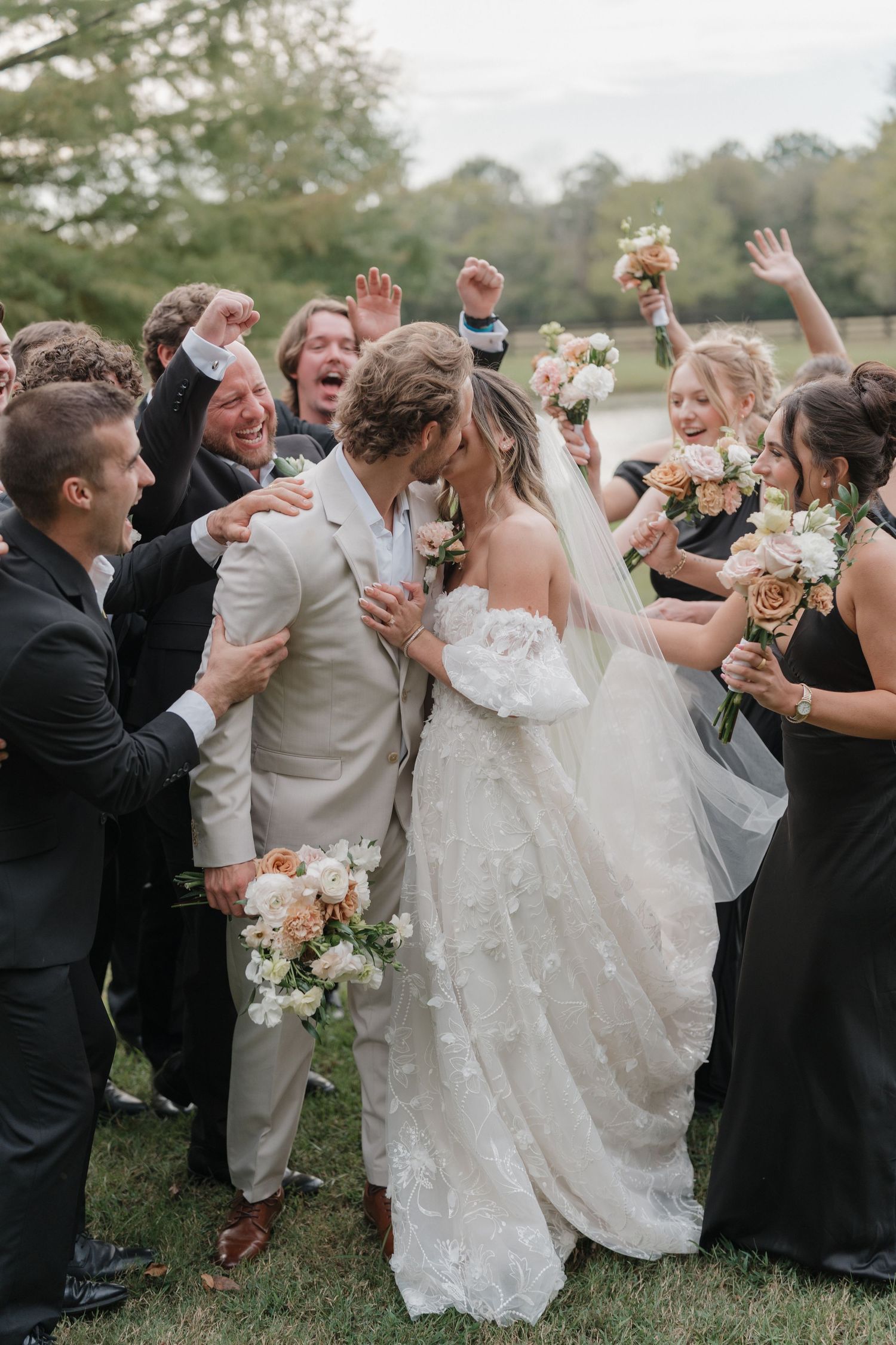 Wedding guests celebrate and cheer as the newlyweds walk through a joyful crowd during an outdoor celebration.
