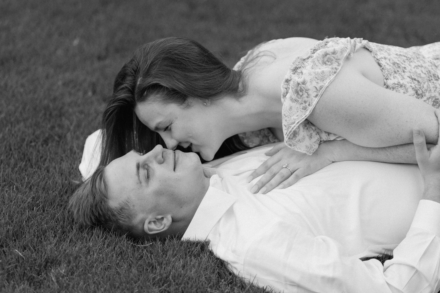 A series of black and white wedding photos showing romantic moments between a couple lying on grass.