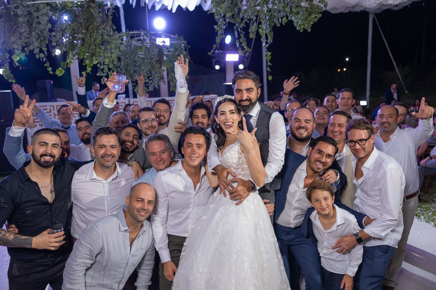 Wedding celebration group photo on illuminated dance floor under decorated tent. Boda en Parras Coahuila fotógrafo