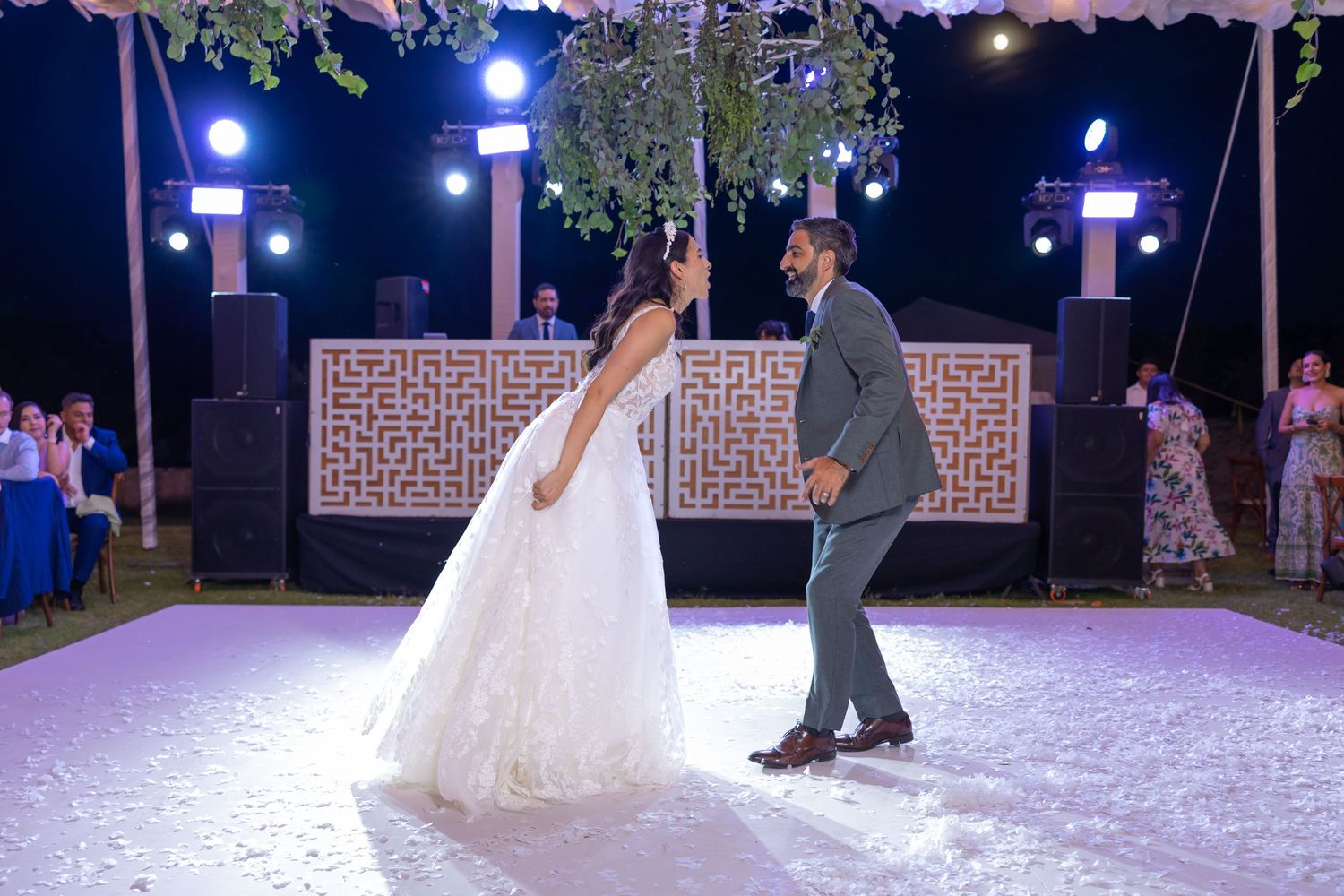 A couple dancing on an illuminated outdoor dance floor under decorative lighting. Boda en Parras Coahuila fotógrafo