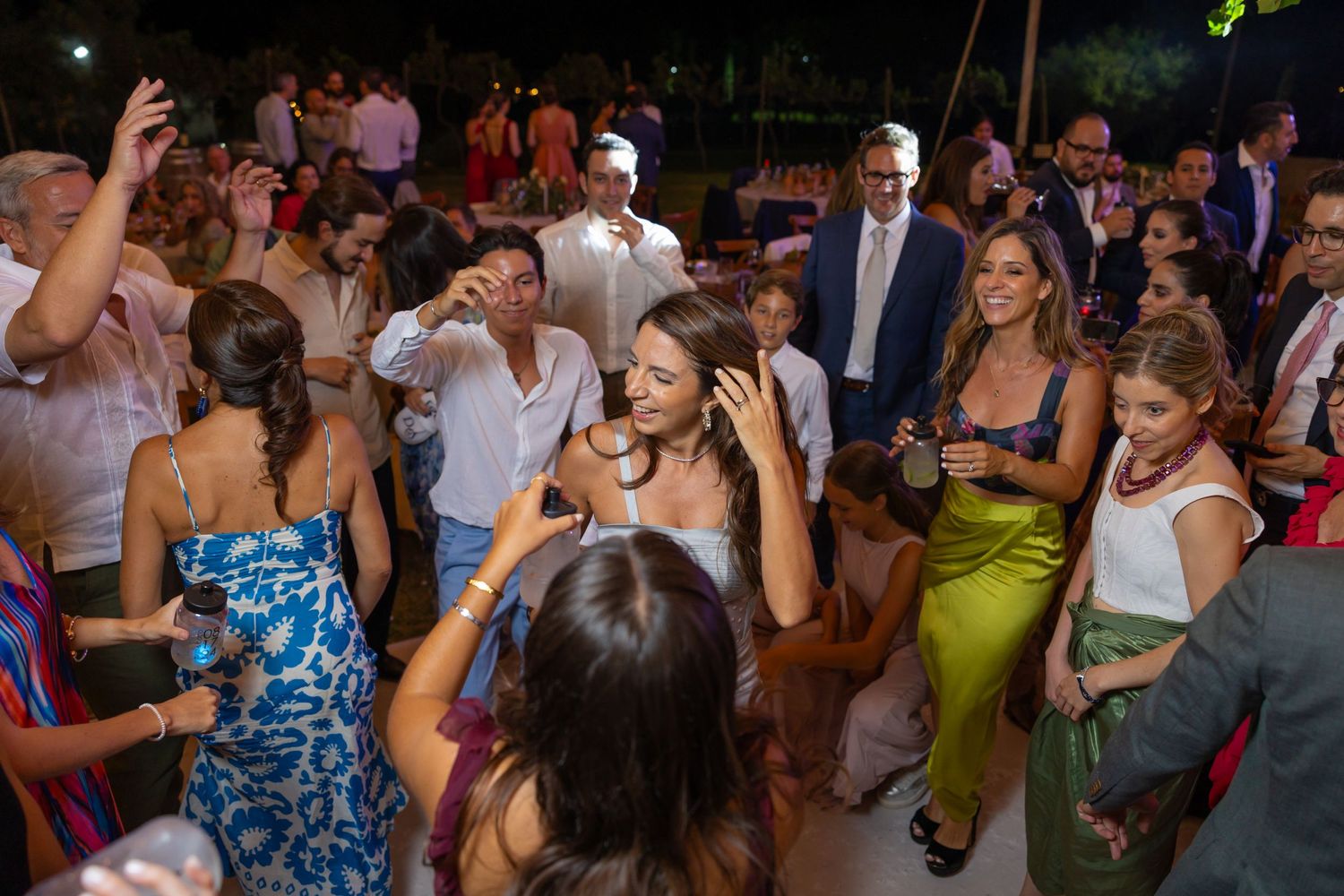 Wedding reception crowd dancing together outdoors under evening lights. Boda en Parras Coahuila fotógrafo