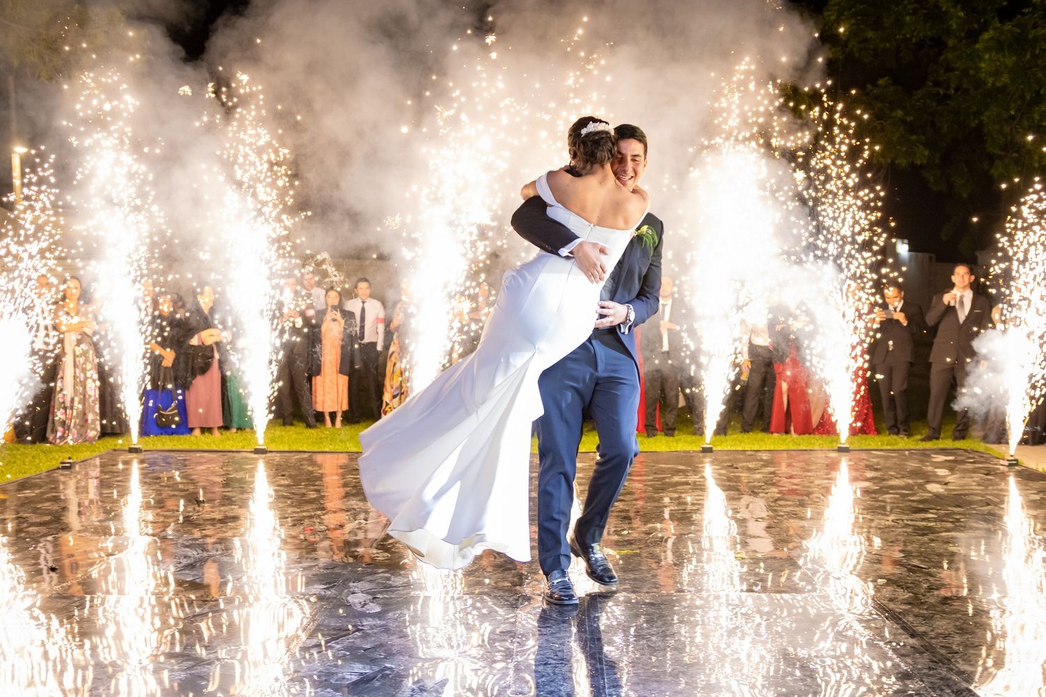Newlyweds dance amid sparkling fountains and pyrotechnics at outdoor wedding celebration. Boda en Parras Coahuila fotógrafo