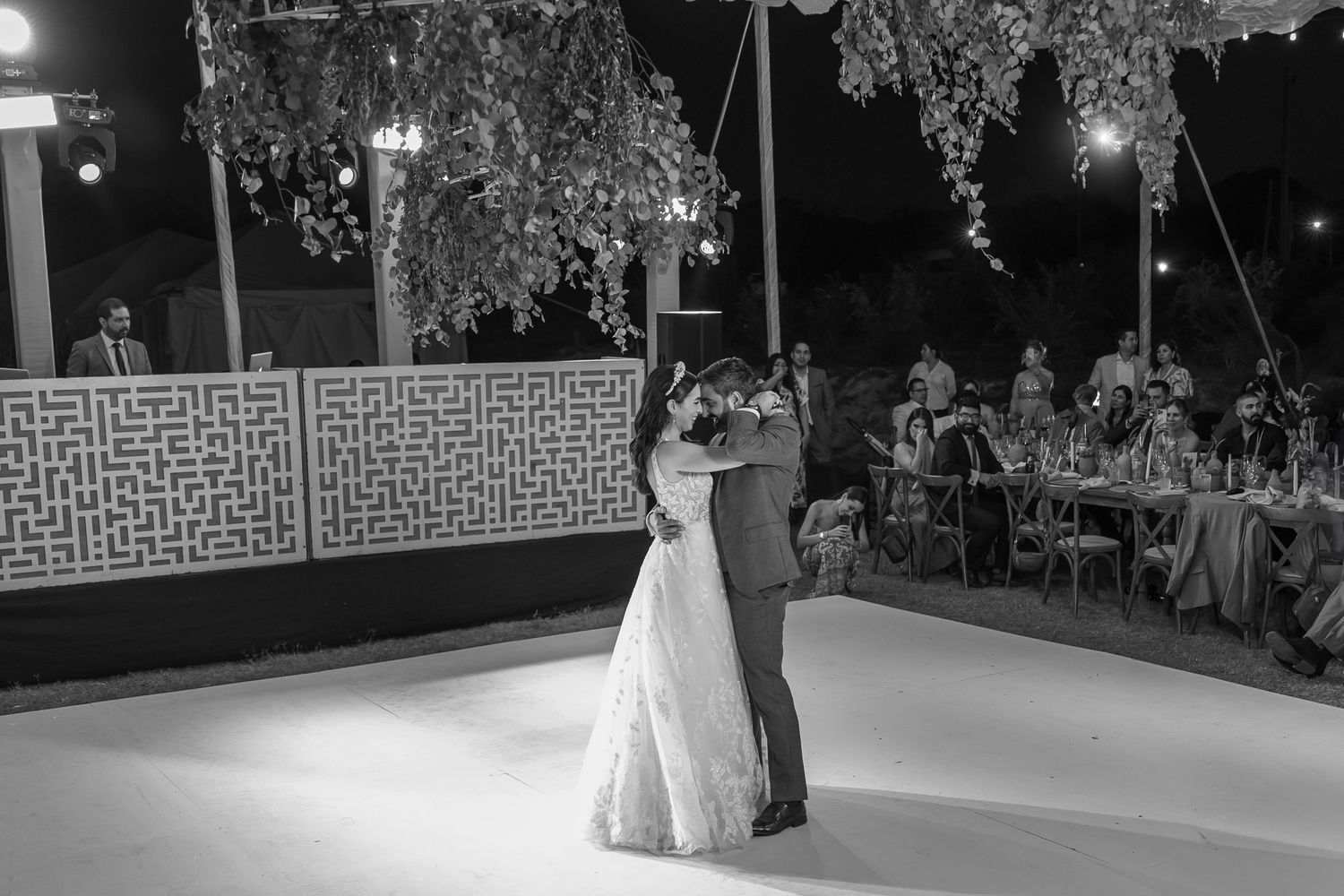 Romantic first dance moment captured in black and white under decorative hanging lights. Boda en Parras Coahuila fotógrafo