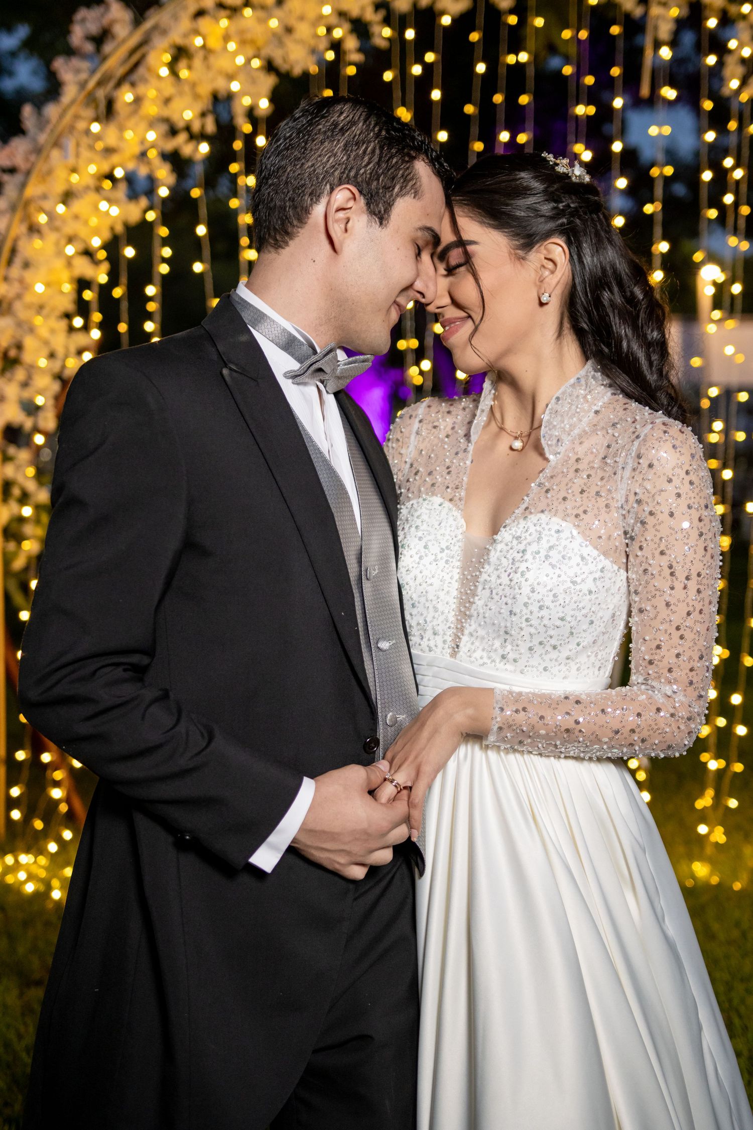 A romantic wedding portrait with fairy lights and a floral arch creating a magical golden backdrop. Boda en Parras Coahuila, Fotógrafo