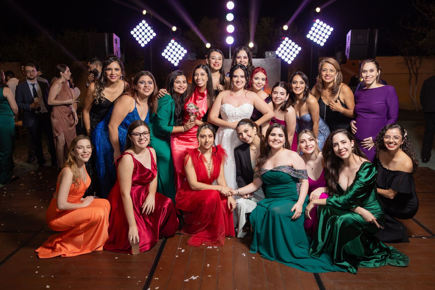 Group photo of wedding party members in colorful formal dresses on illuminated dance floor. Boda en Parras Coahuila, Fotógrafo de bodas,