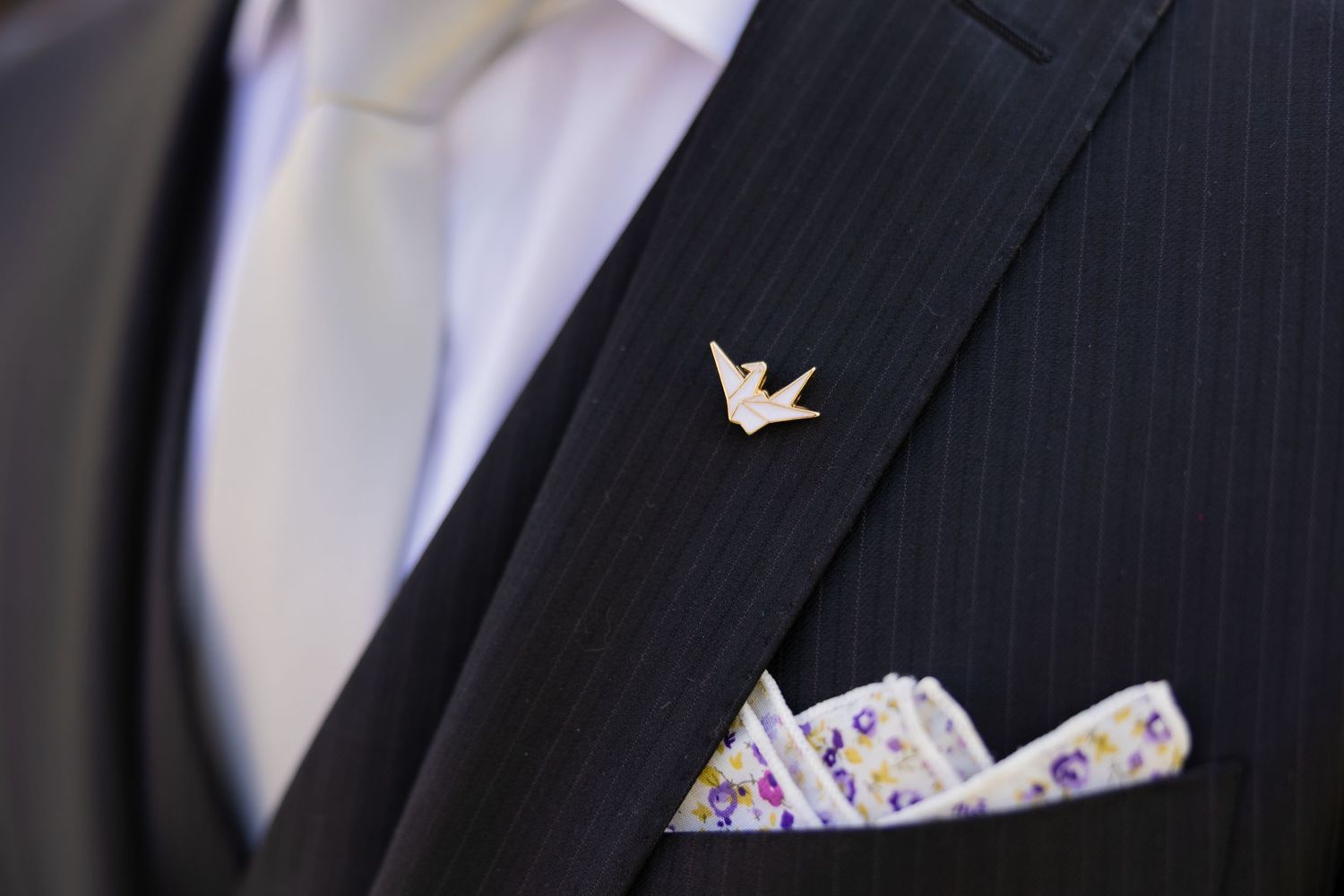 Close-up detail of a white dove pin and patterned pocket square on a dark suit jacket. Boda en Parras Coahuila, Fotógrafo de bodas
