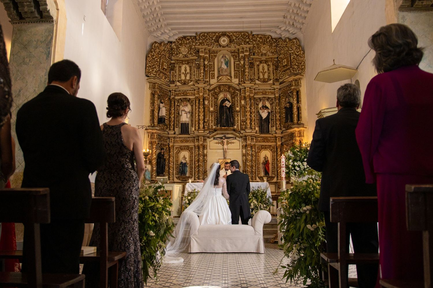 Wedding ceremony in a church with an ornate golden altar and religious statues. Boda en Parras Coahuila, Fotógrafo de bodas