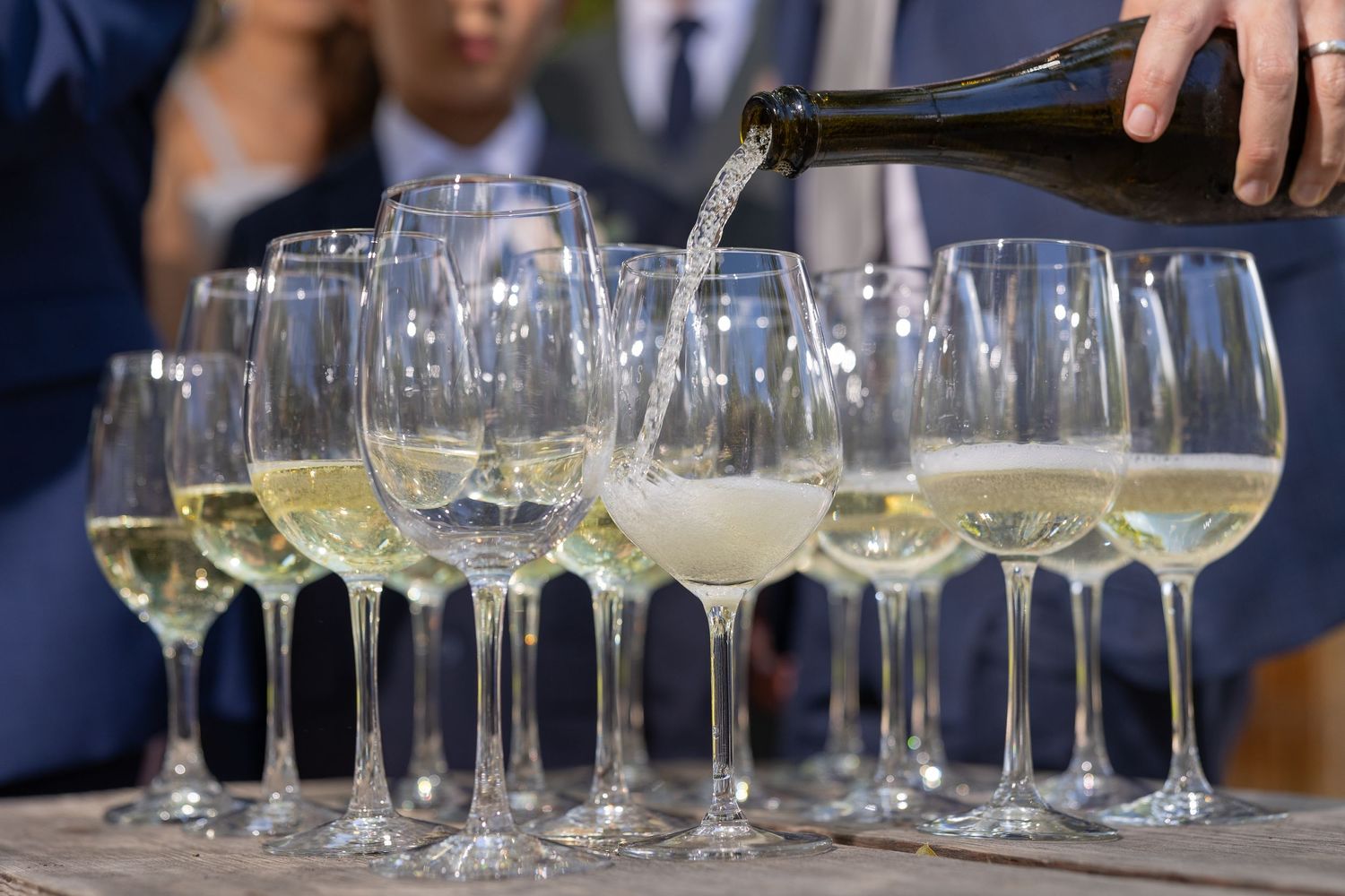 White wine being poured into multiple wine glasses at an event. Boda en Parras Coahuila fotógrafo