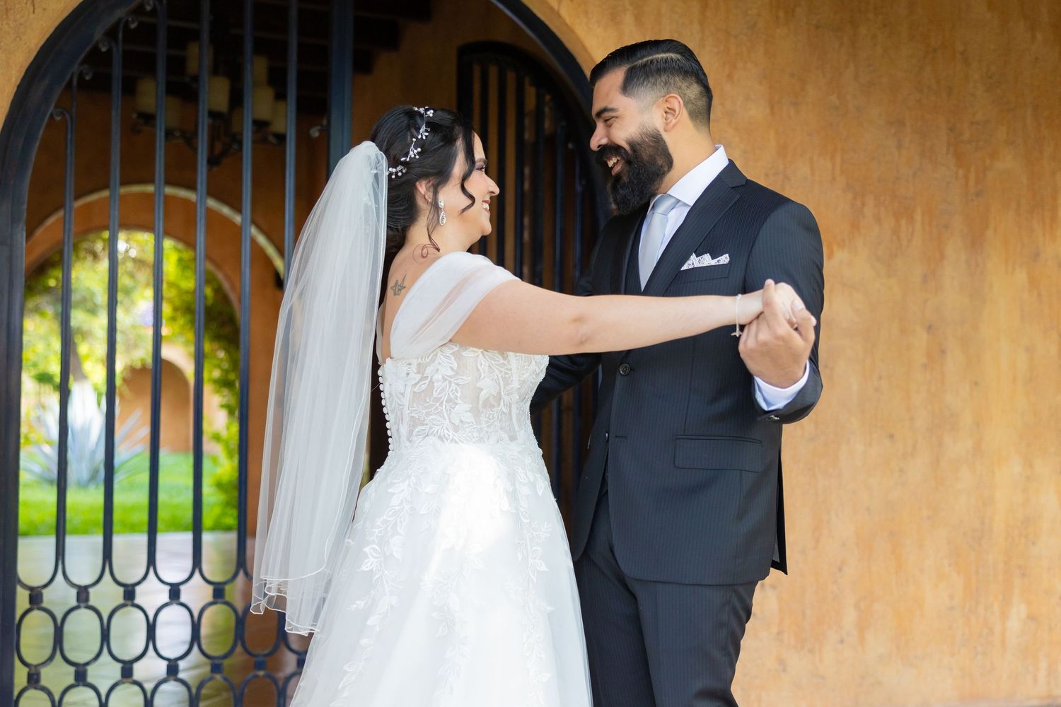 A couple dances together in front of an ornate iron gate during their wedding. Boda en Parras Coahuila, Fotógrafo de bodas