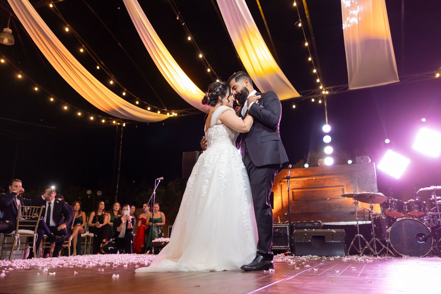 Newlyweds dance beneath elegant draped fabric and string lights during their wedding reception. Boda en Parras Coahuila, Fotógrafo de bodas