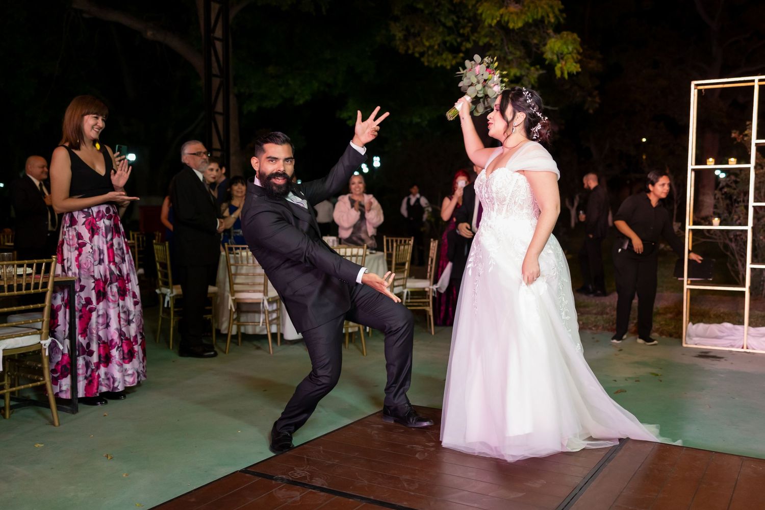 Couple performs energetic dance moves during their first dance at an outdoor wedding reception on a lit dance floor. Boda en Parras Coahuila
