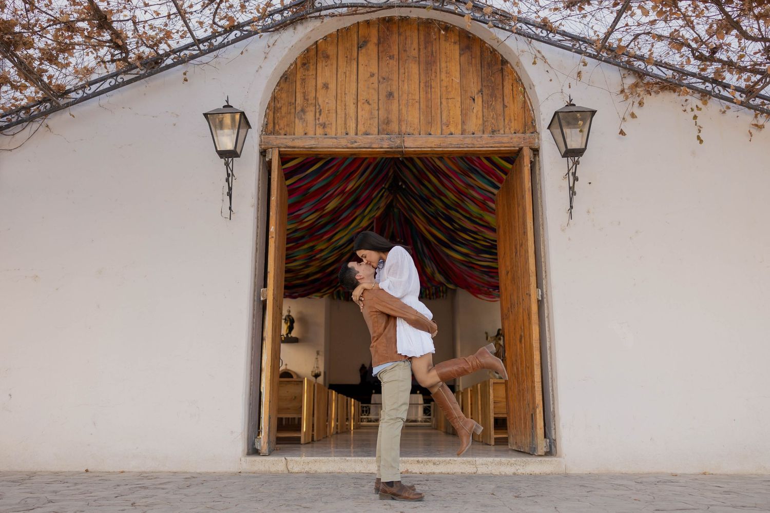 A series of rustic wooden doorways with lanterns and white stucco walls creates an old-world architectural aesthetic.