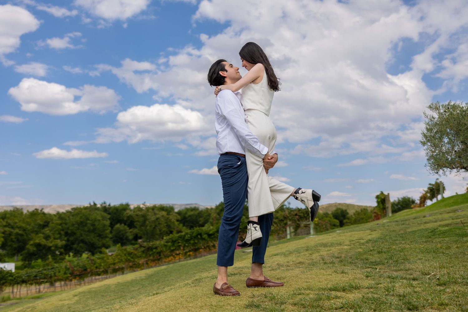 A romantic lift pose captured on a sunny hillside with blue skies and white clouds. Propuesta de matrimonio Parras, Fotografo
