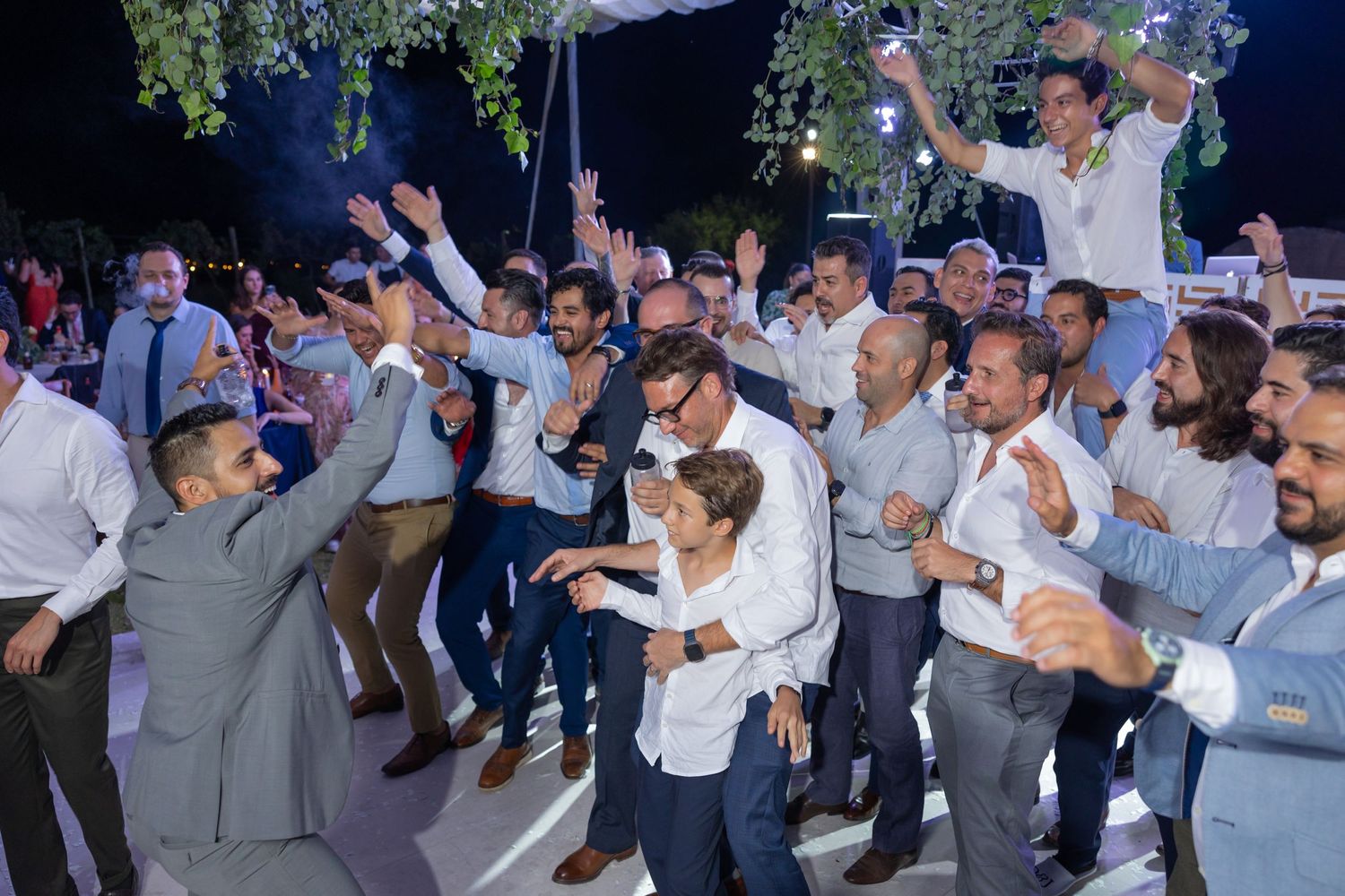 Large group of male wedding guests dancing and celebrating enthusiastically on the dance floor. Boda en Parras Coahuila fotógrafo