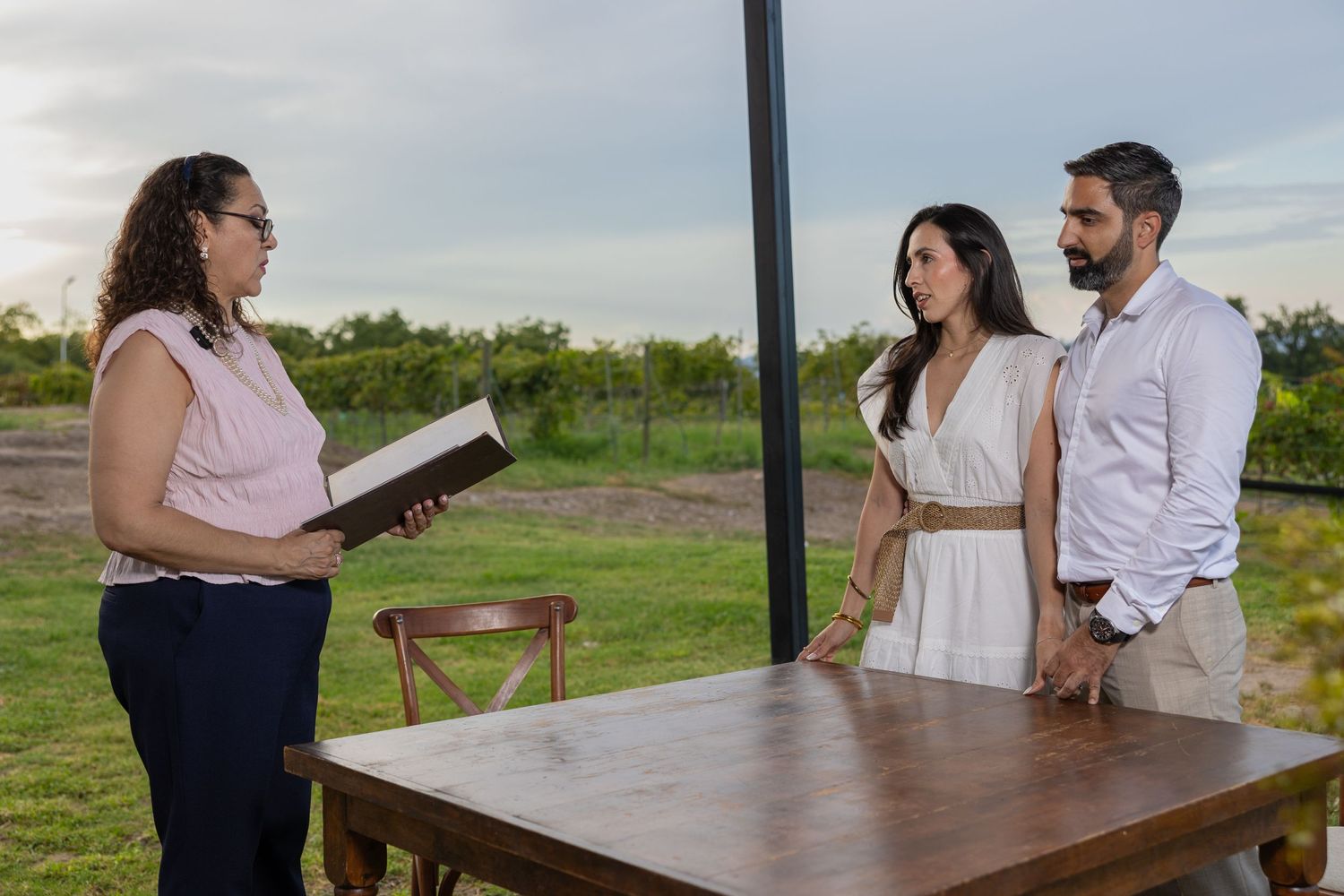 An outdoor ceremony taking place at a wooden table with mountains in the background. Boda en Parras Coahuila fotógrafo